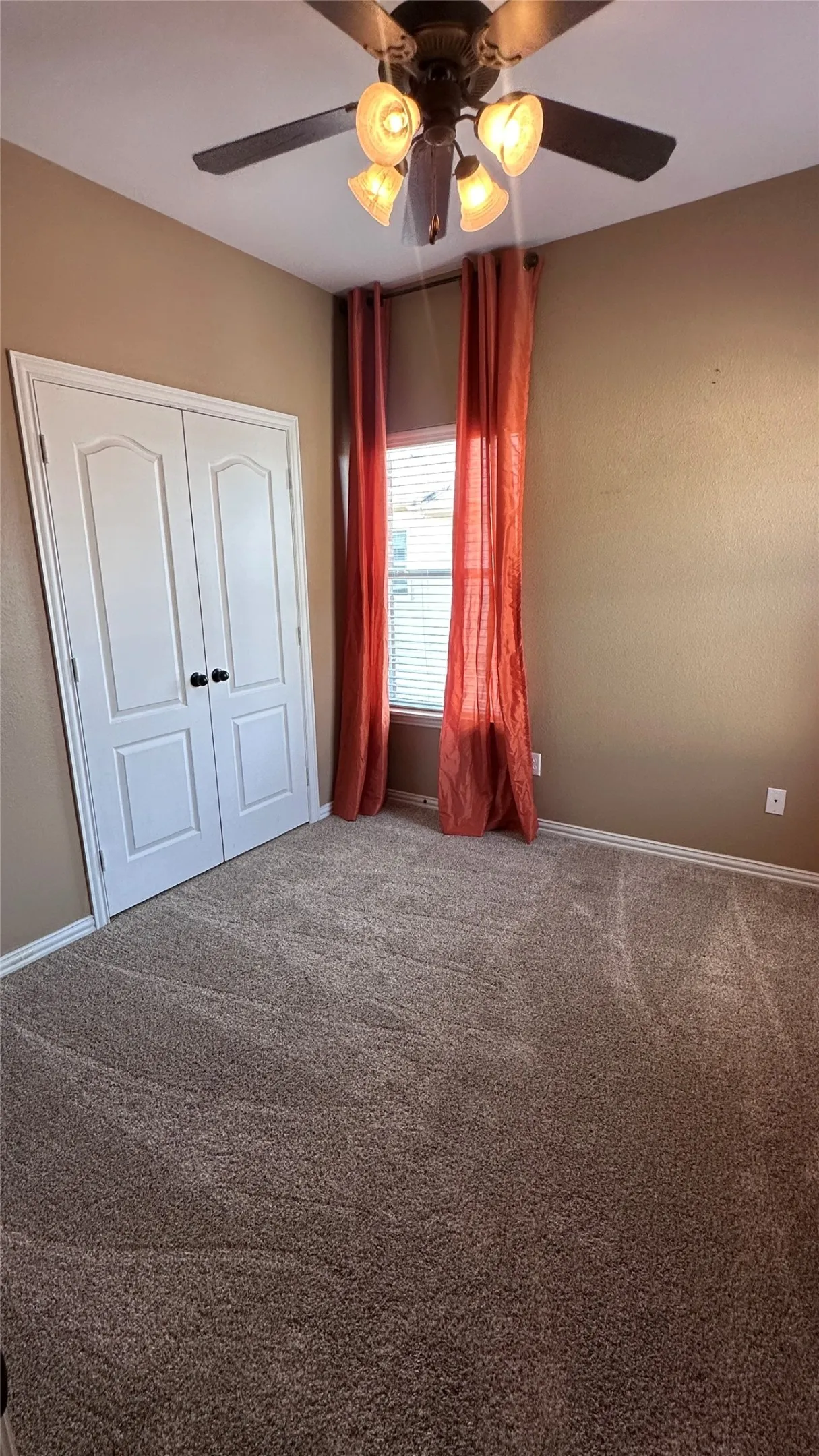 Textured carpeting, window with blinds, bi-fold closet doors, and ceiling fan with integrated lighting