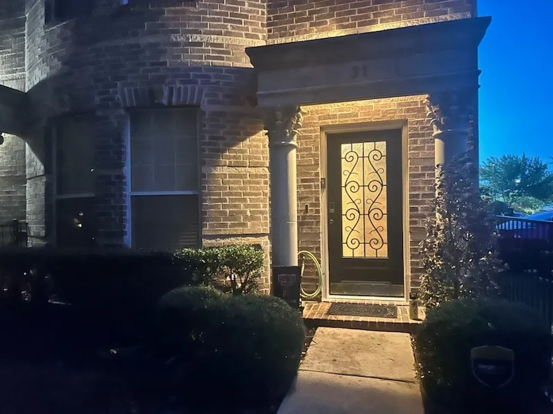 Brick exterior with a decorative glass-paneled entry door, flanked by two architectural columns, and a stone entryway