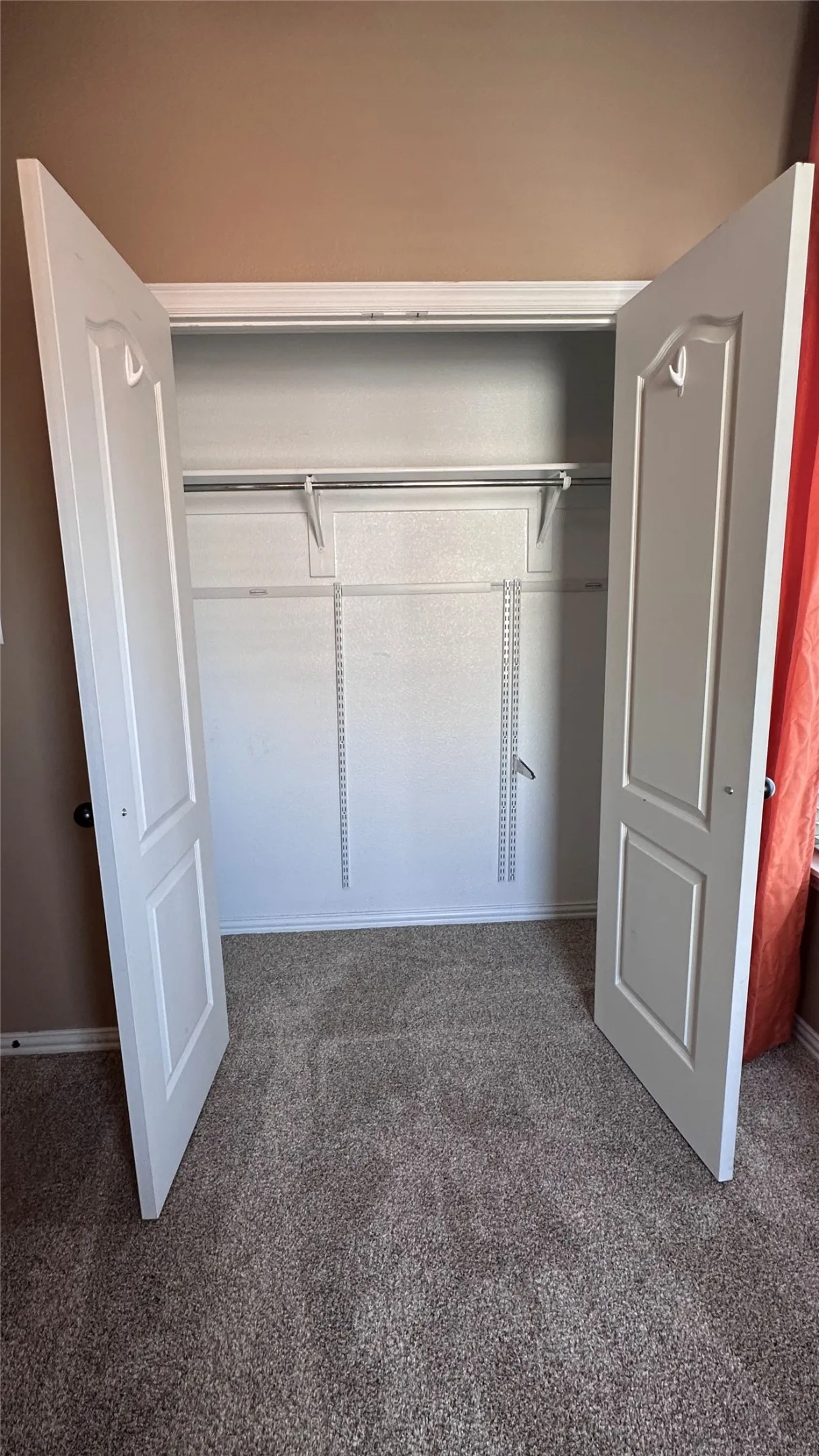 Double bifold doors opening to a closet with adjustable wire shelving and a metal hanging rod