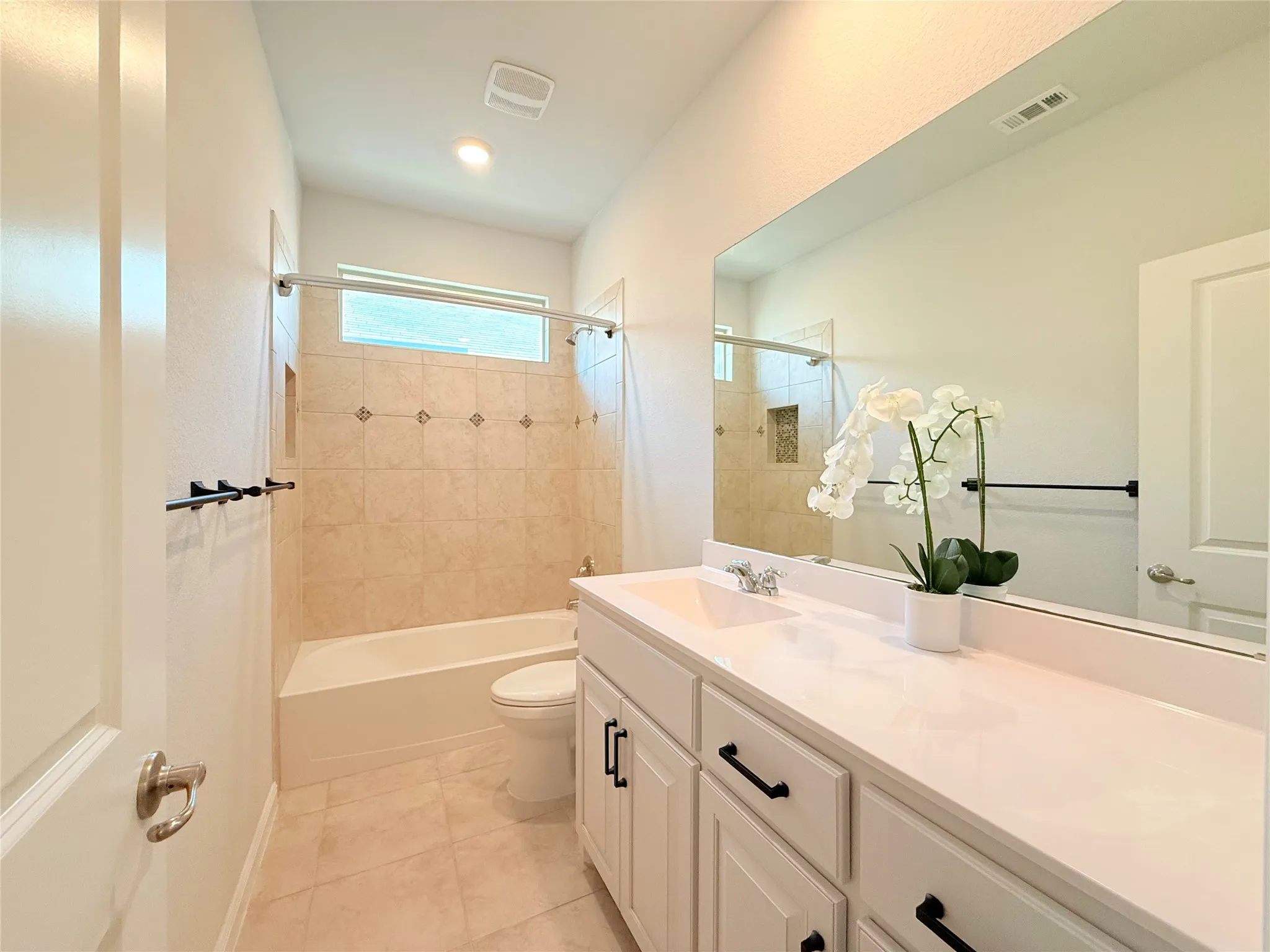 Single vanity with white cabinetry and black hardware, white countertop, and expansive mirror