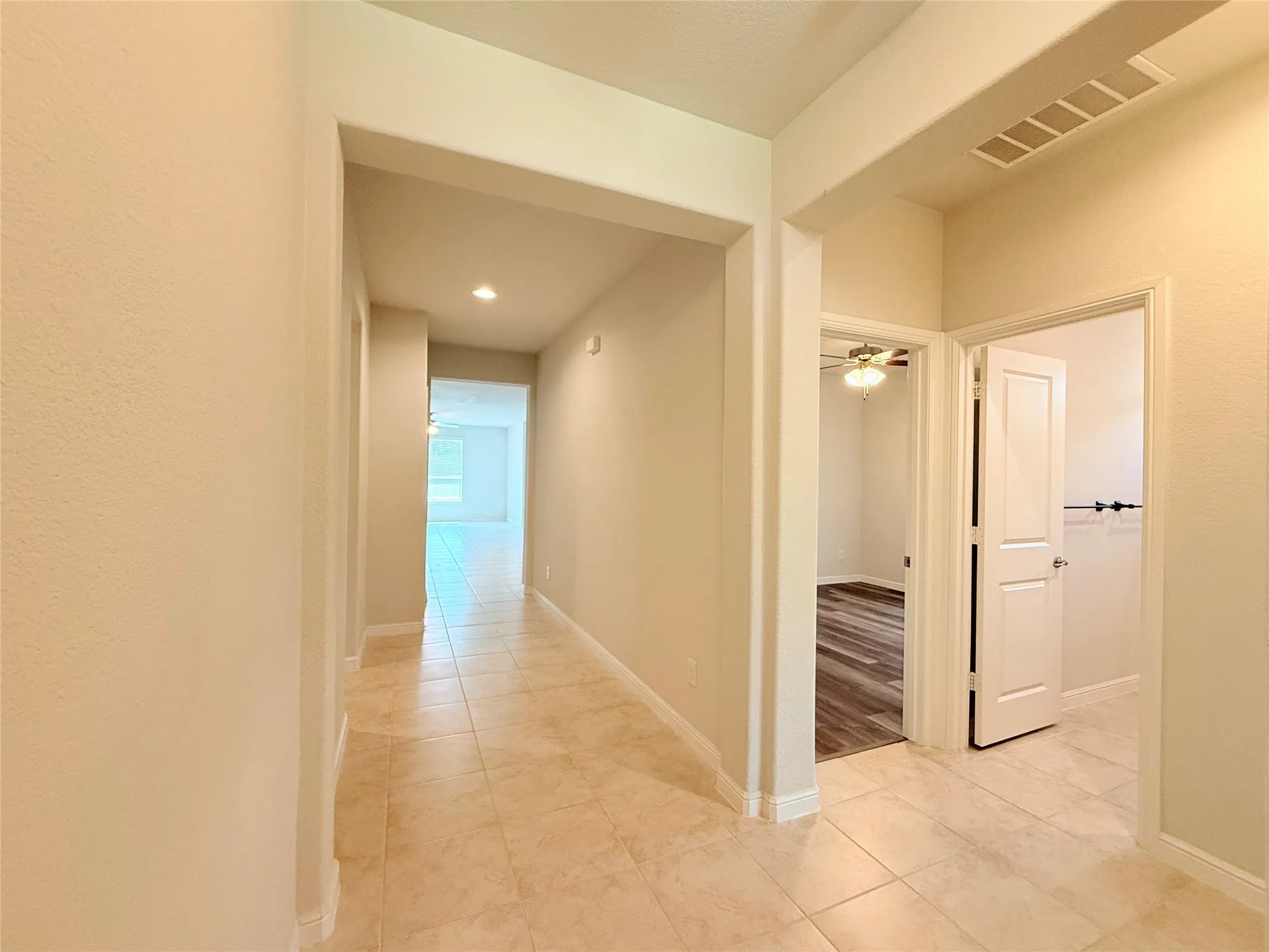 Tiled flooring throughout the hallway, recessed lighting, and white paneled doors