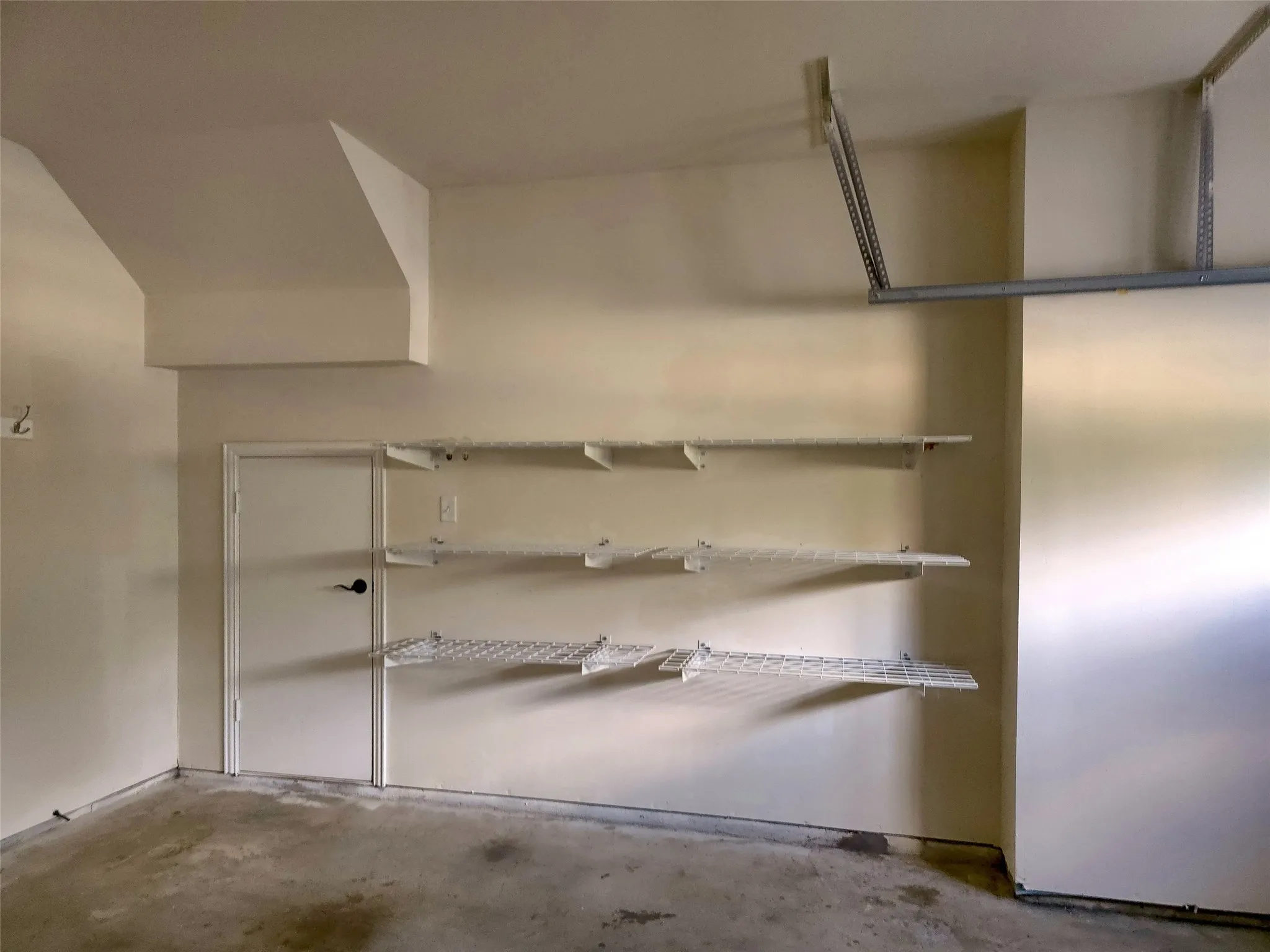 Wall-mounted shelving system with a white door and concrete flooring