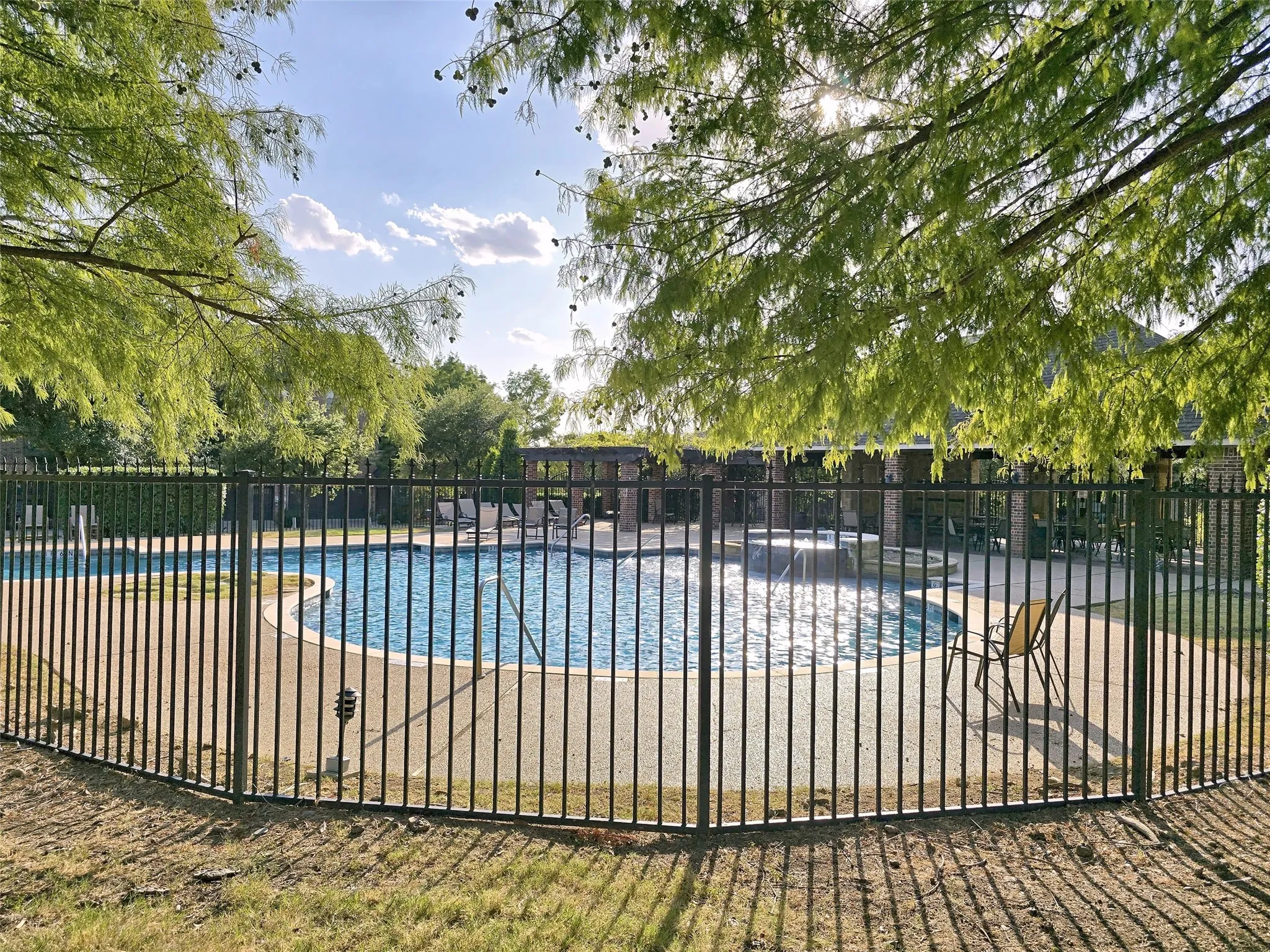 Fenced pool area with a curved edge and a concrete surround
