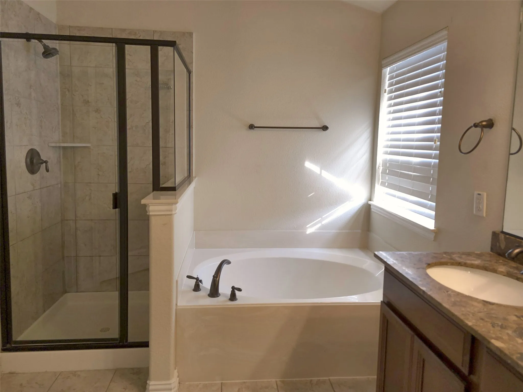 Shower enclosure with dark bronze frame, tiled walls, and built-in shelf