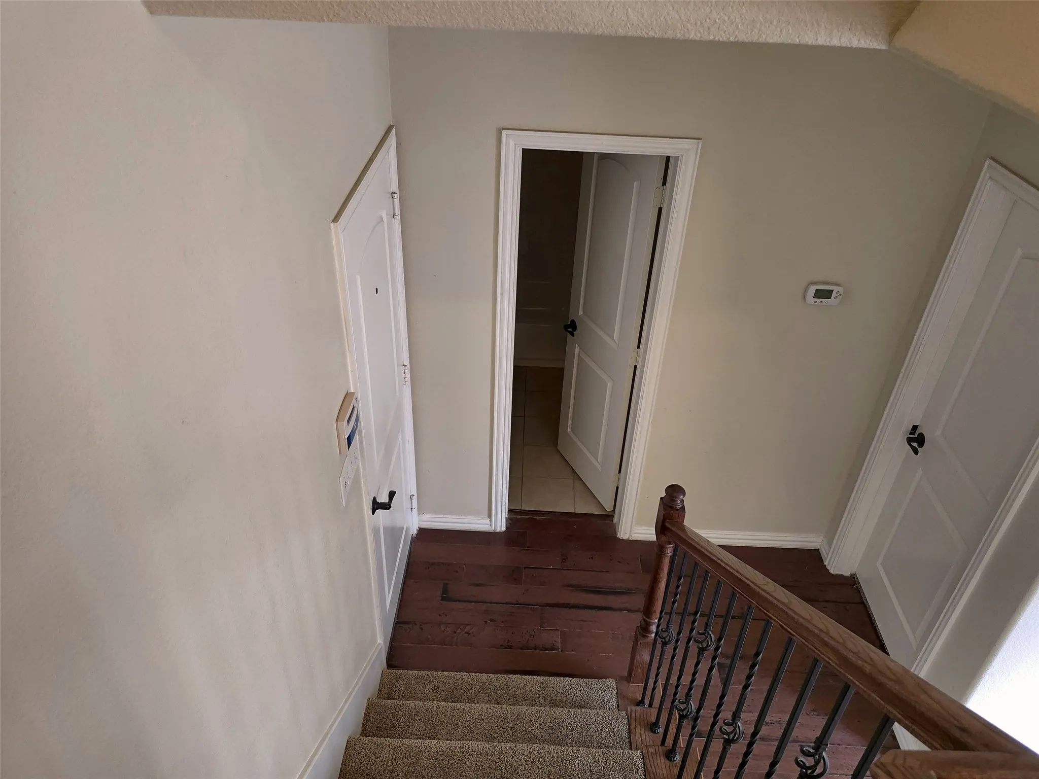 Carpeted staircase with an ornamental metal baluster and wood handrail