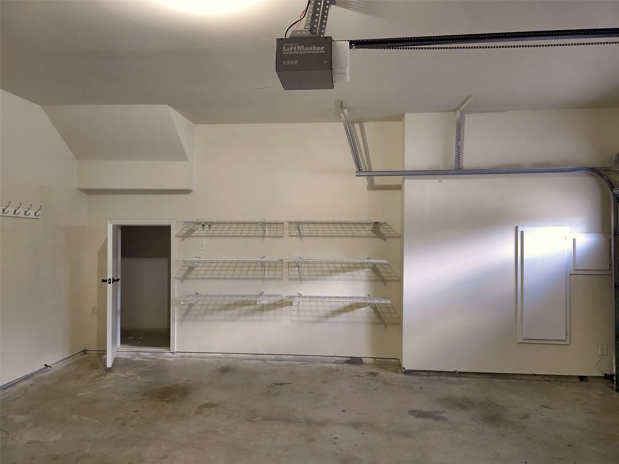 Attached garage with built-in wire shelving, overhead storage racks, and a garage door opener