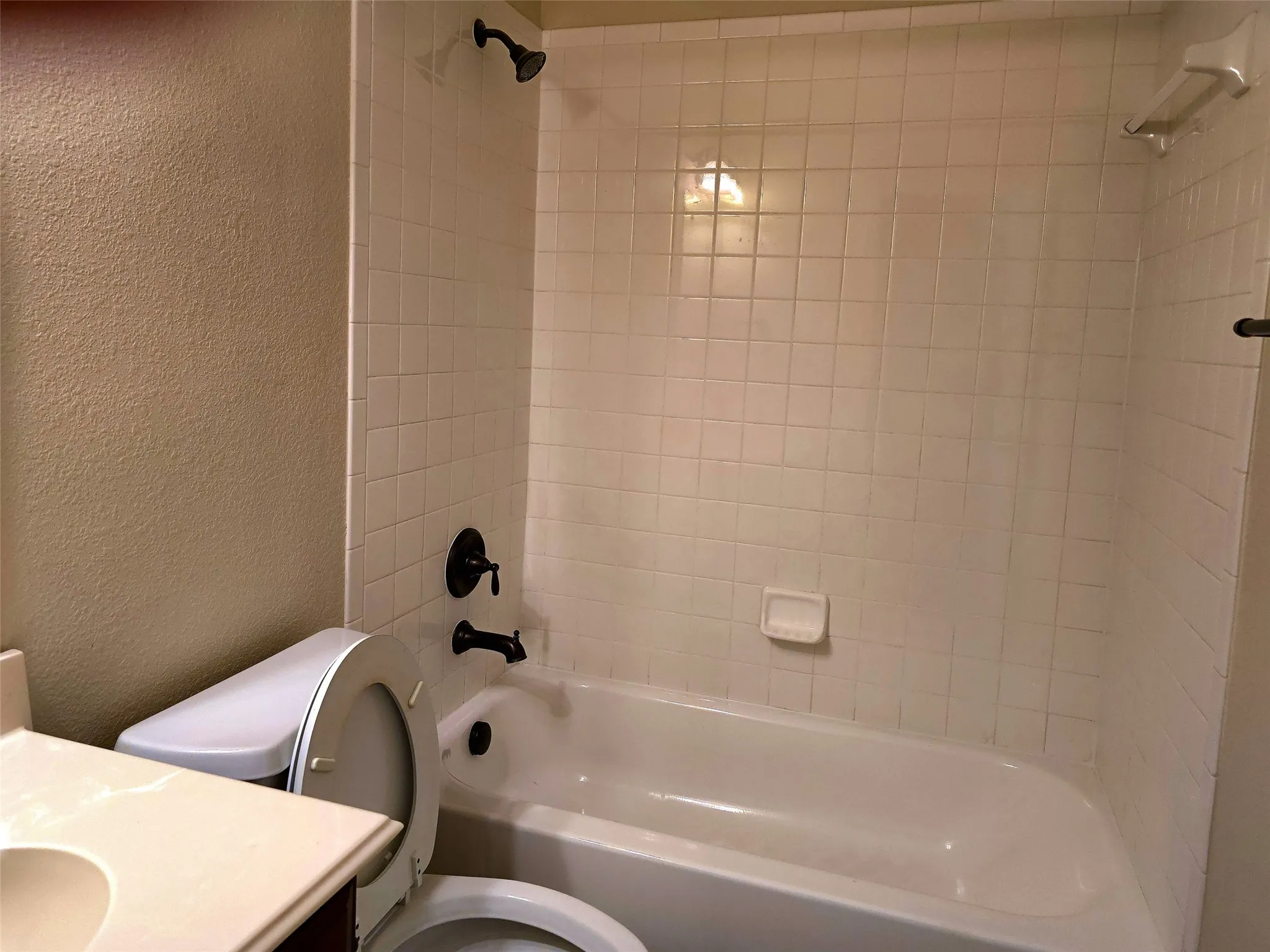 Tub-shower combination with white tile surround and dark bronze fixtures