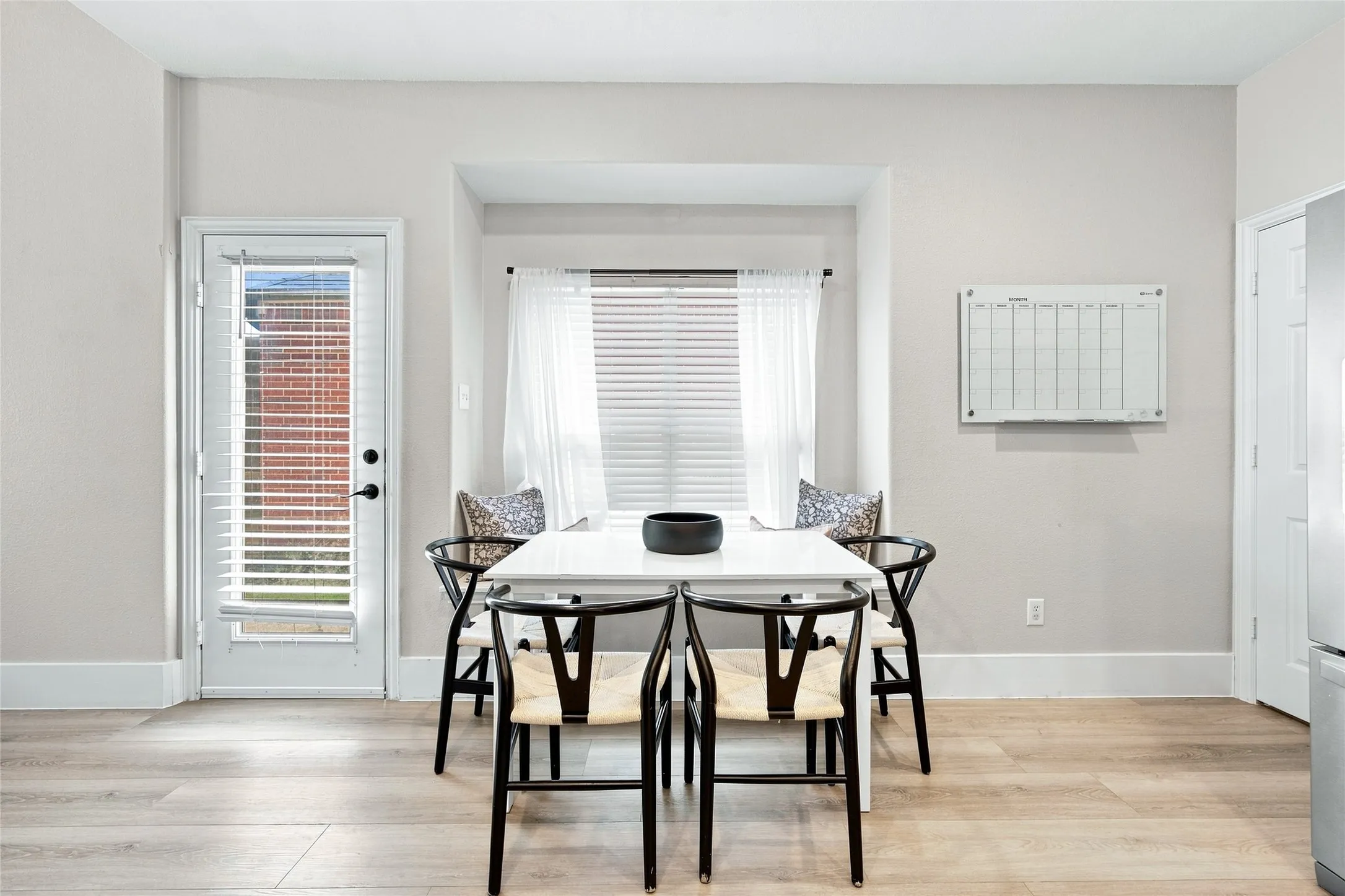 Breakfast area boasts recessed window alcove with integrated seating.  Back door allows plenty of natural light into the home along with the large window.