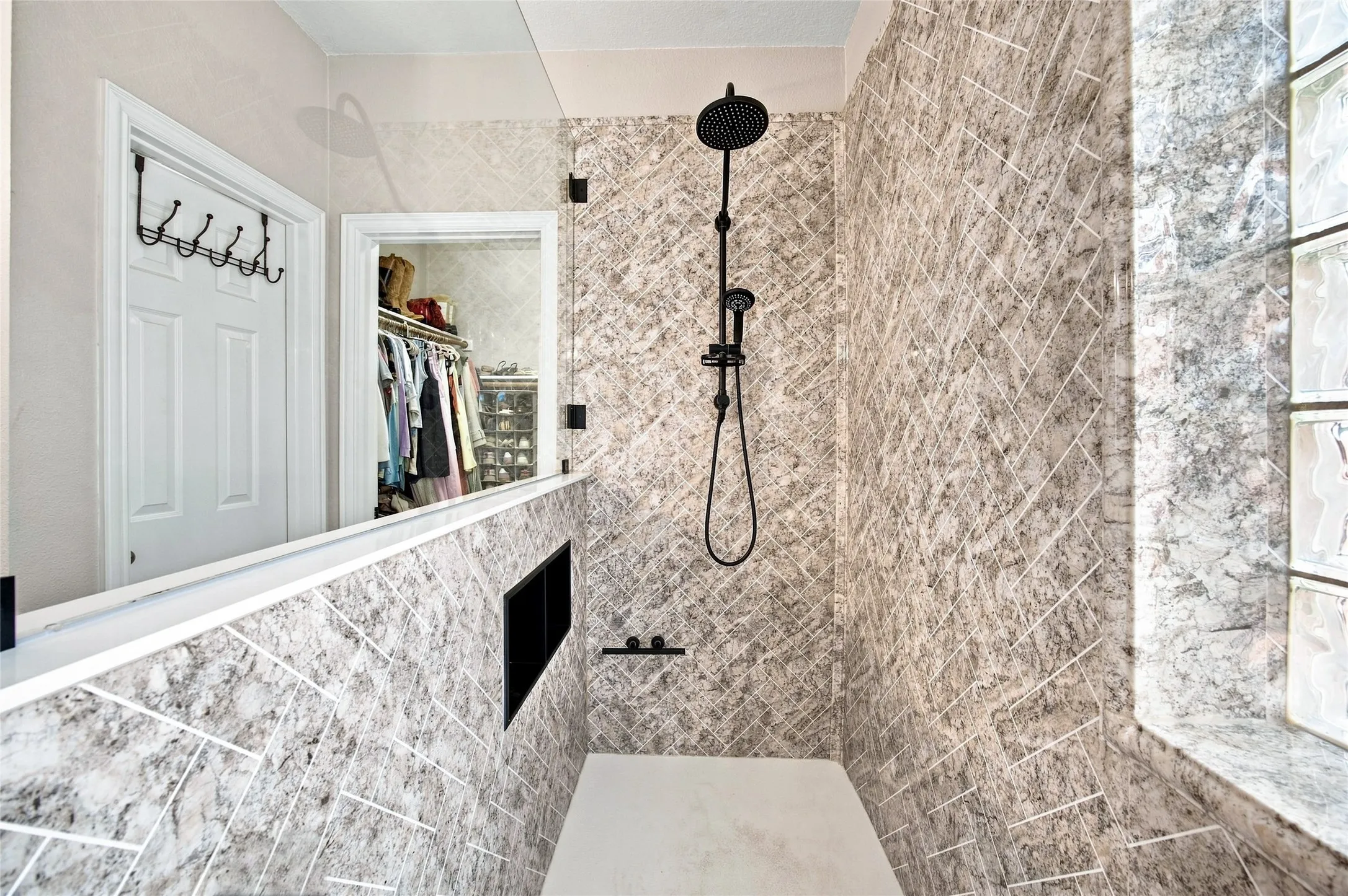 New custom shower enclosure with matte black fixtures, an integrated shower niche, and glass block window