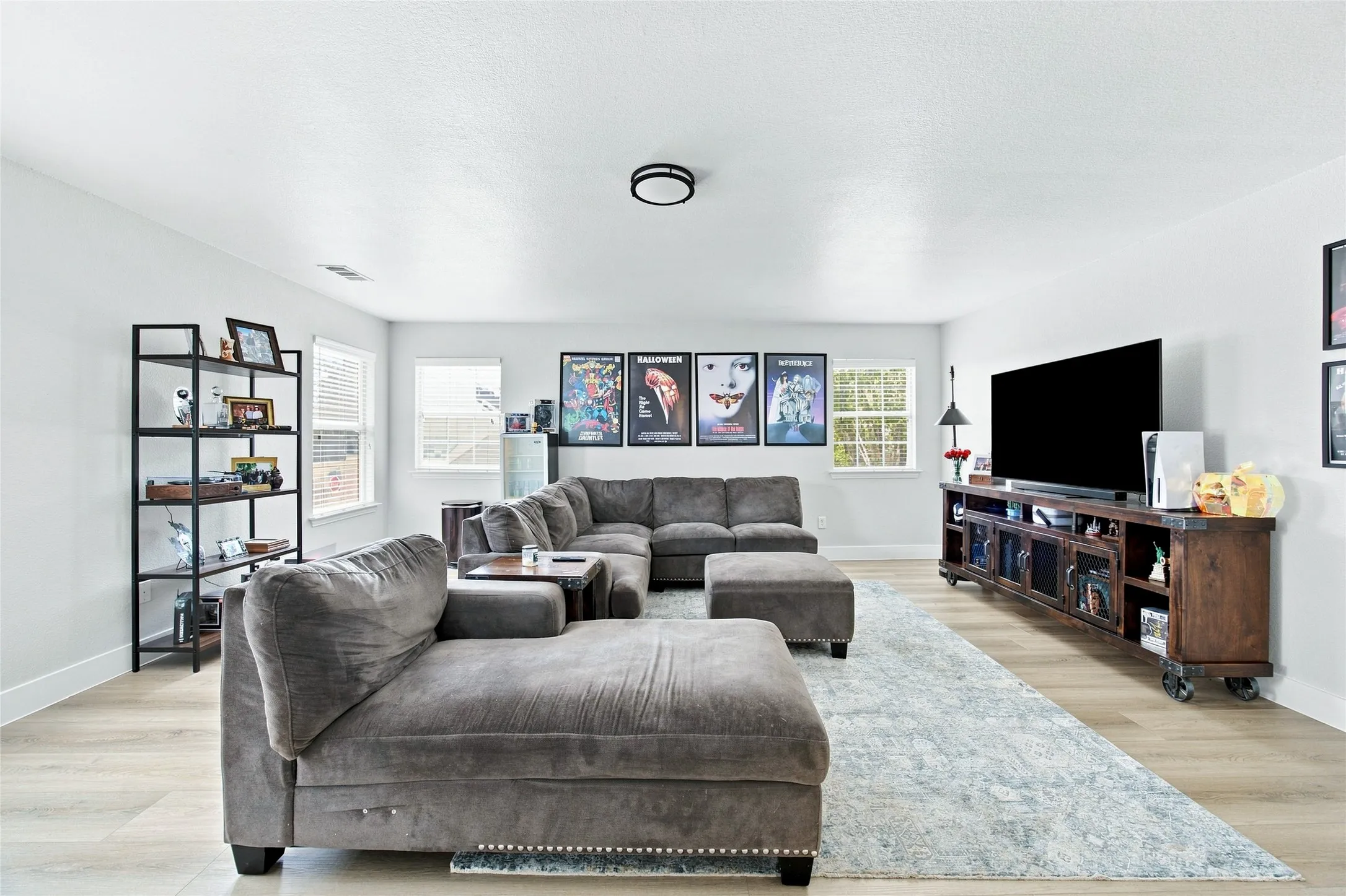 Spacious living/game room area featuring light wood-finish flooring, multiple windows. Great space for entertaining, large enough to accomodate all your friends and family.