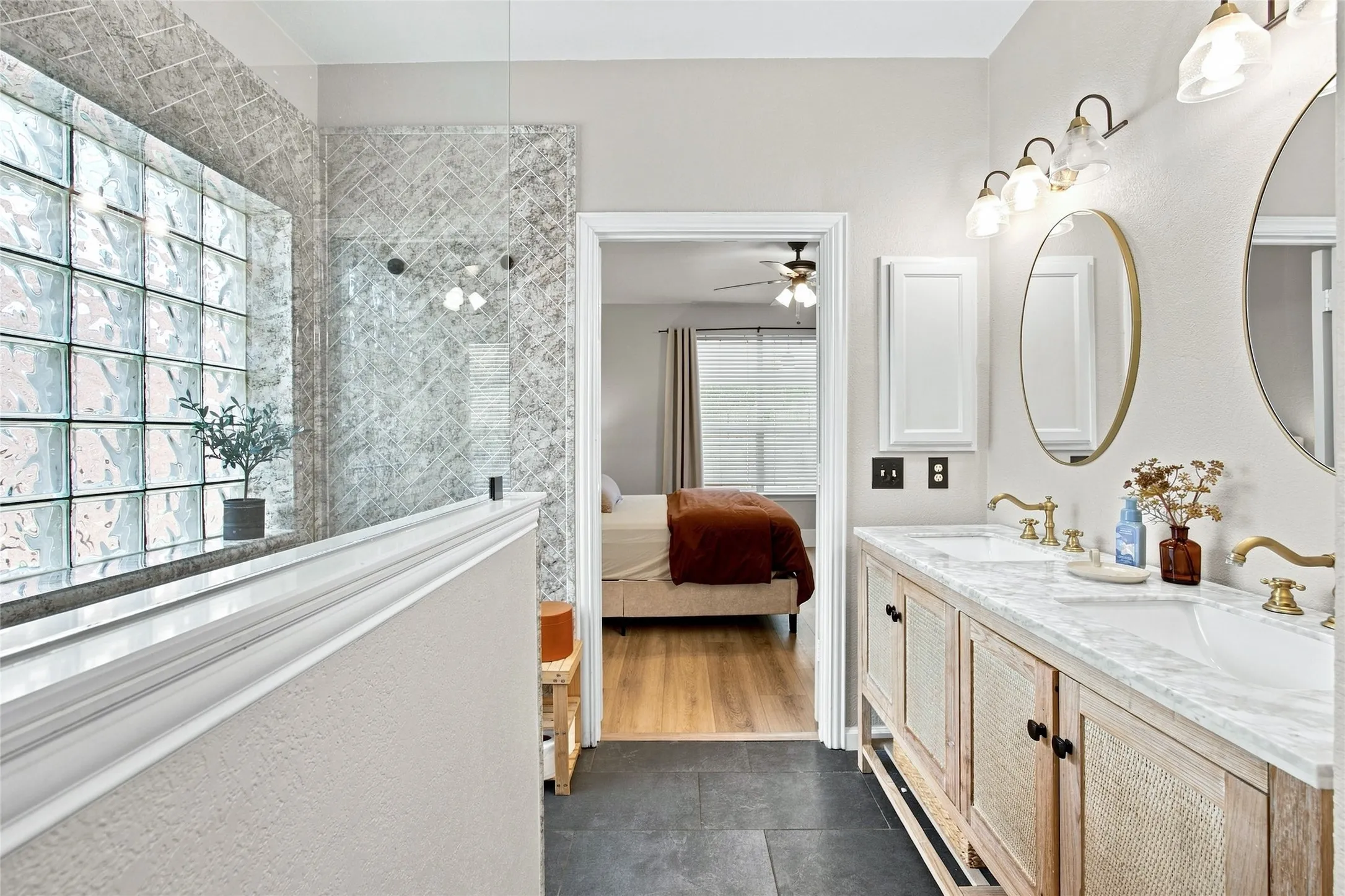 Completely remodeled ensuite bathroom boasts a beautiful dual vanity with integrated sinks and gold-tone fixtures, under-mount cabinet storage, wall-mounted medicine cabinet, and overhead sconce lighting and massive walk in shower.