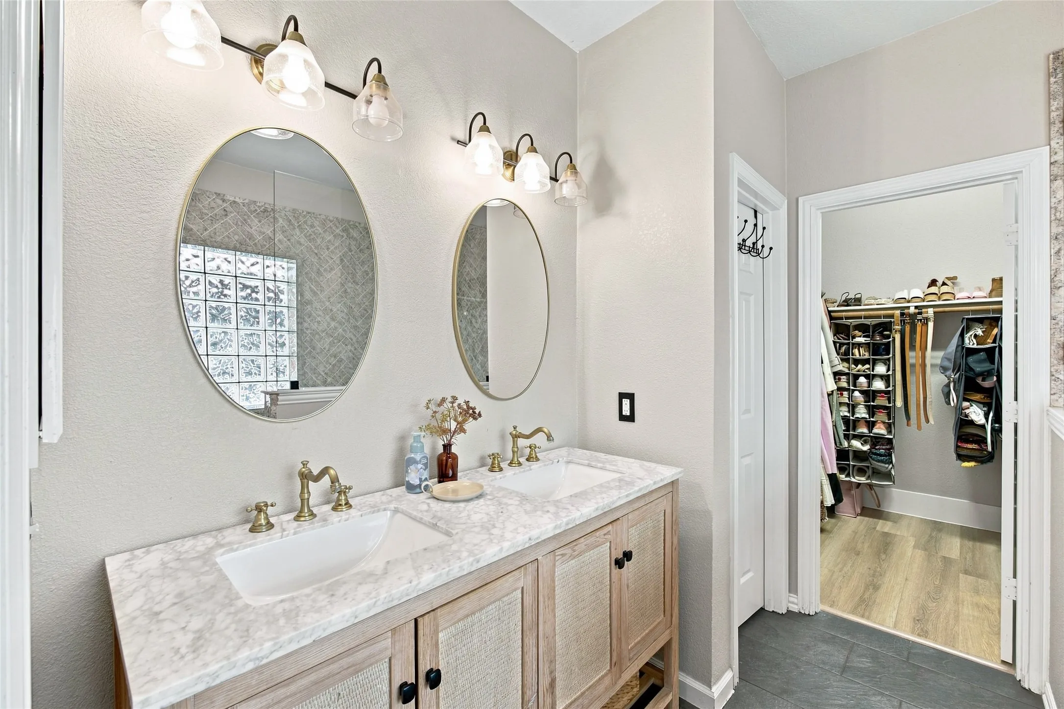 Additional view of ensuite bathroom showing off the elegant vanity and a peak into the large walk in closet at the end of the  room.  Notice the exquisite choice of bathroom fixtures on the vanity as well as the matching mirrors.