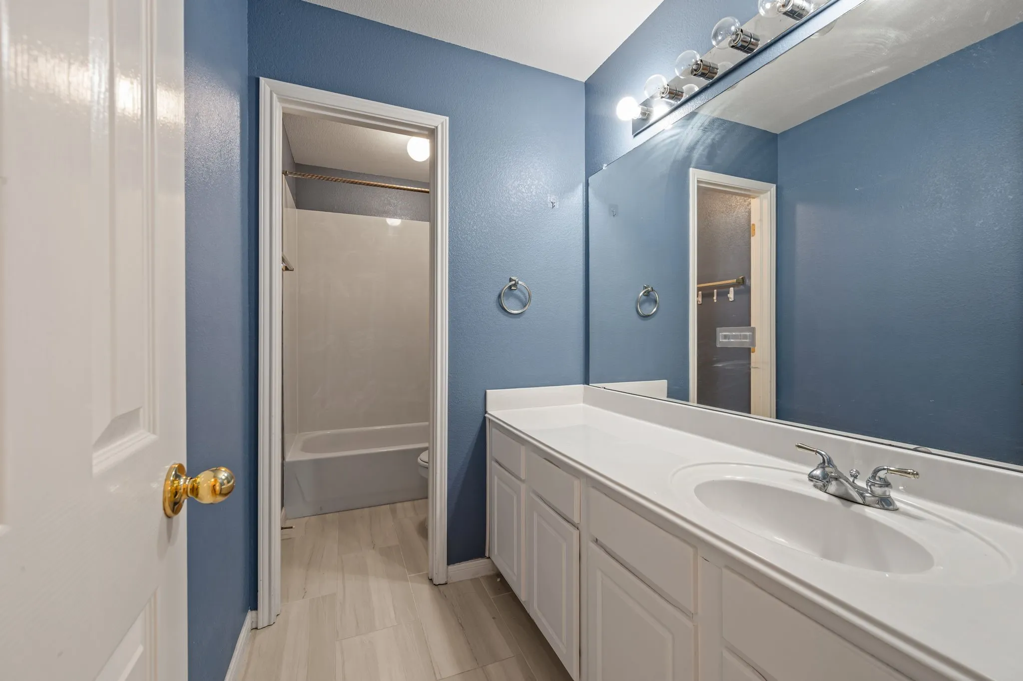Spacious vanity featuring double basin sink, expansive mirror, and built-in white cabinetry