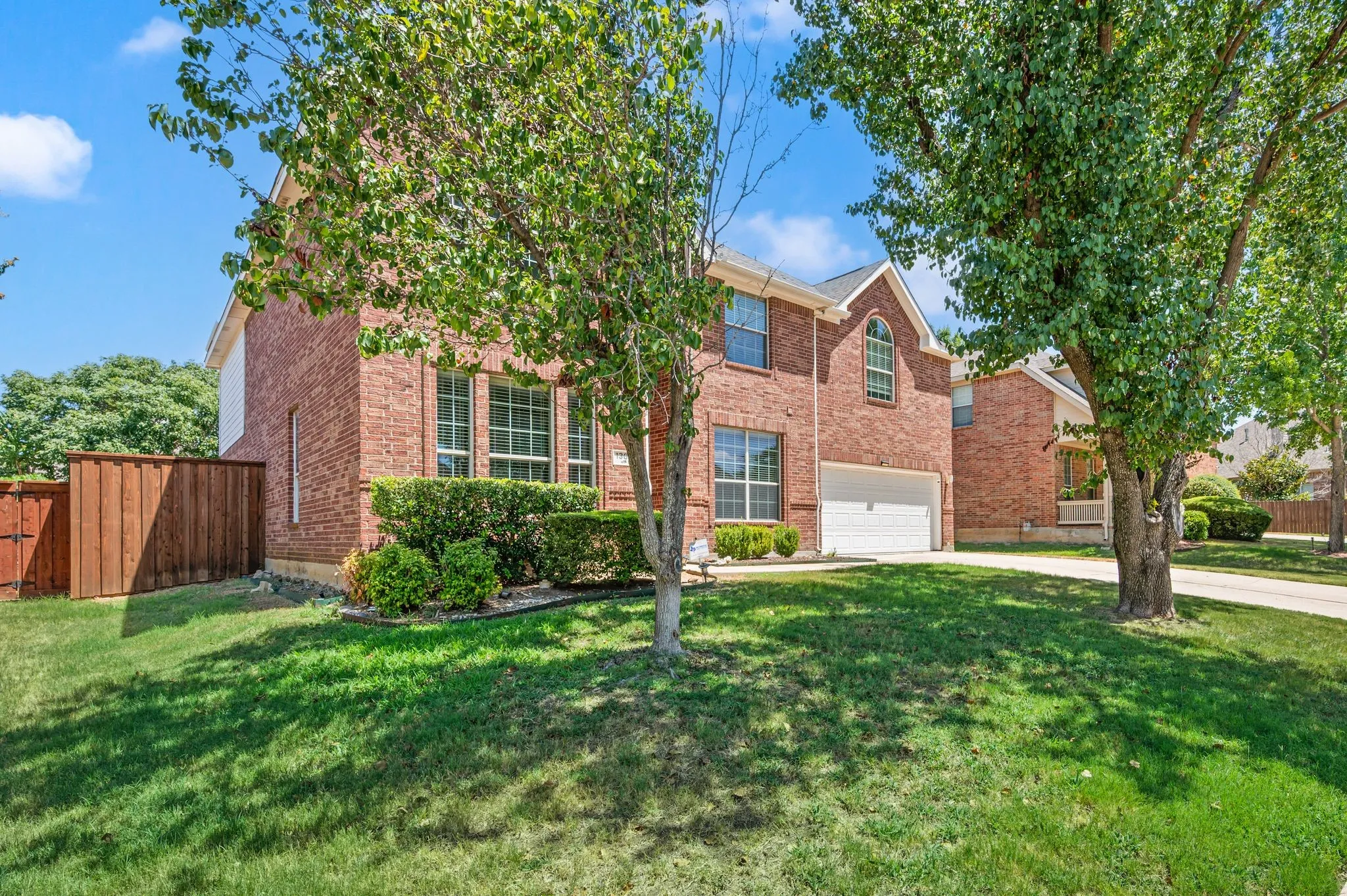Brick exterior with multiple windows, attached garage, and a lush lawn