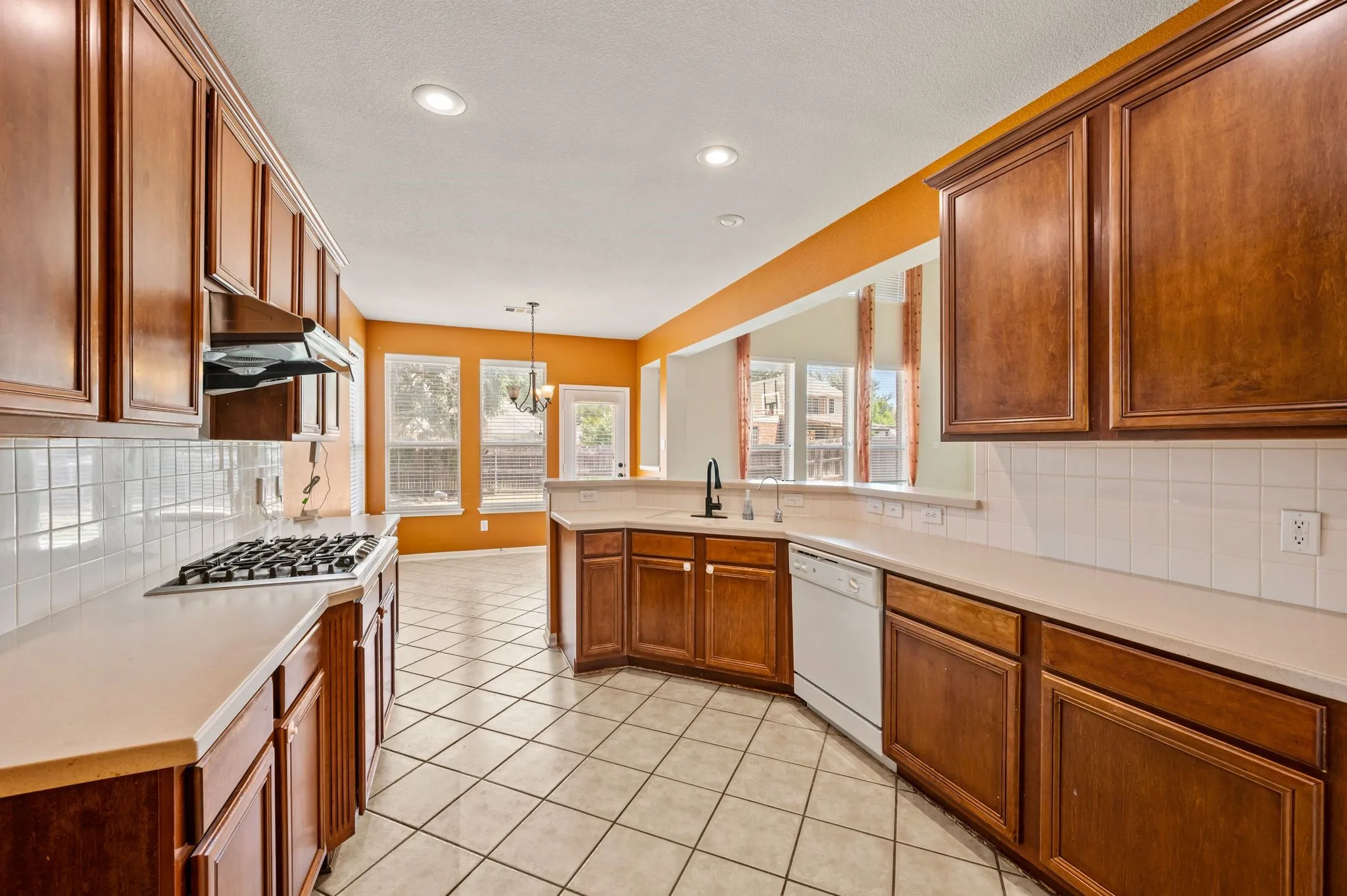 Kitchen featuring wood cabinetry, light-colored countertops, white subway tile backsplash, and stainless steel appliances