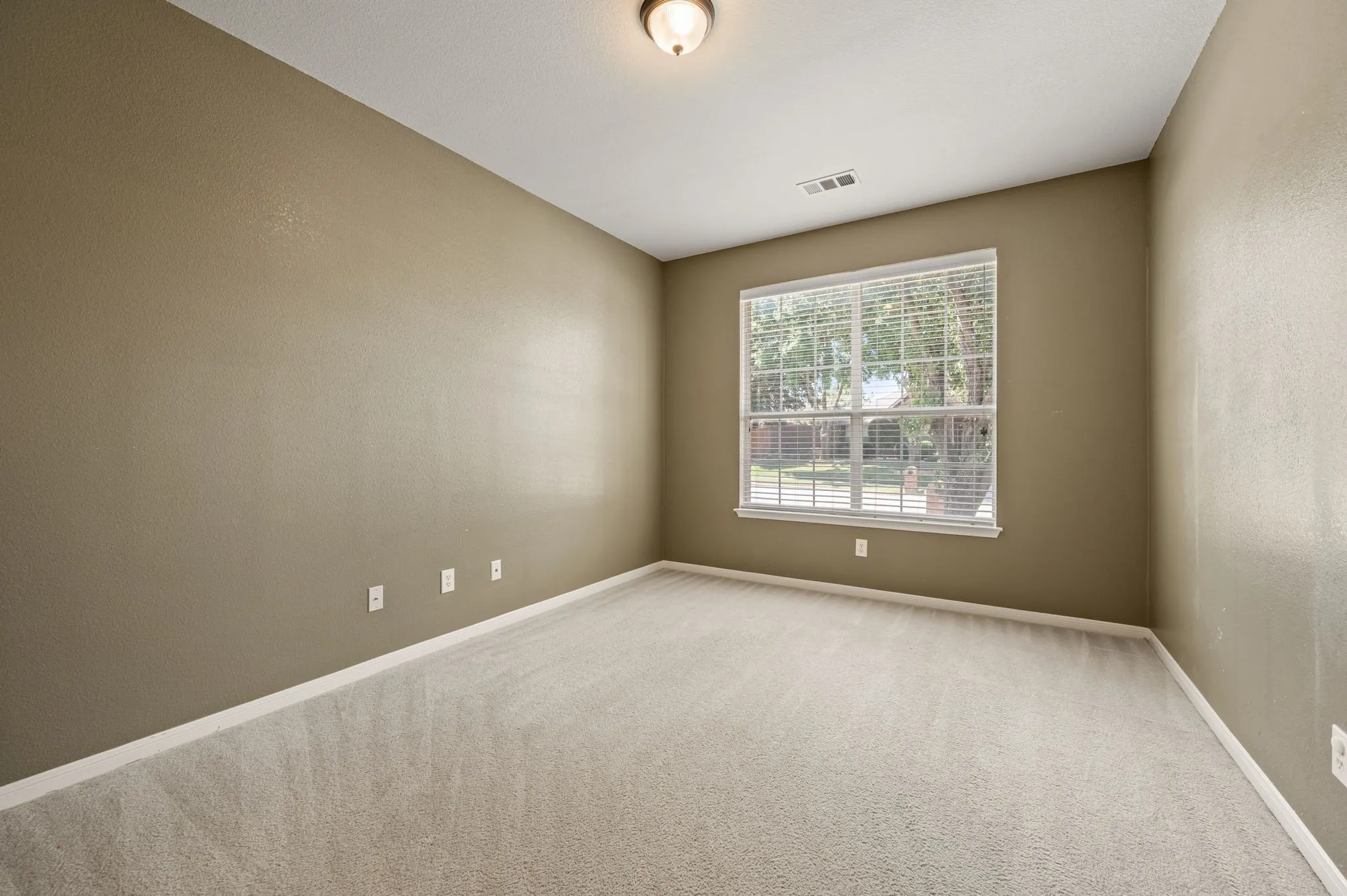 Carpeted room with neutral wall paint and a single window featuring horizontal blinds