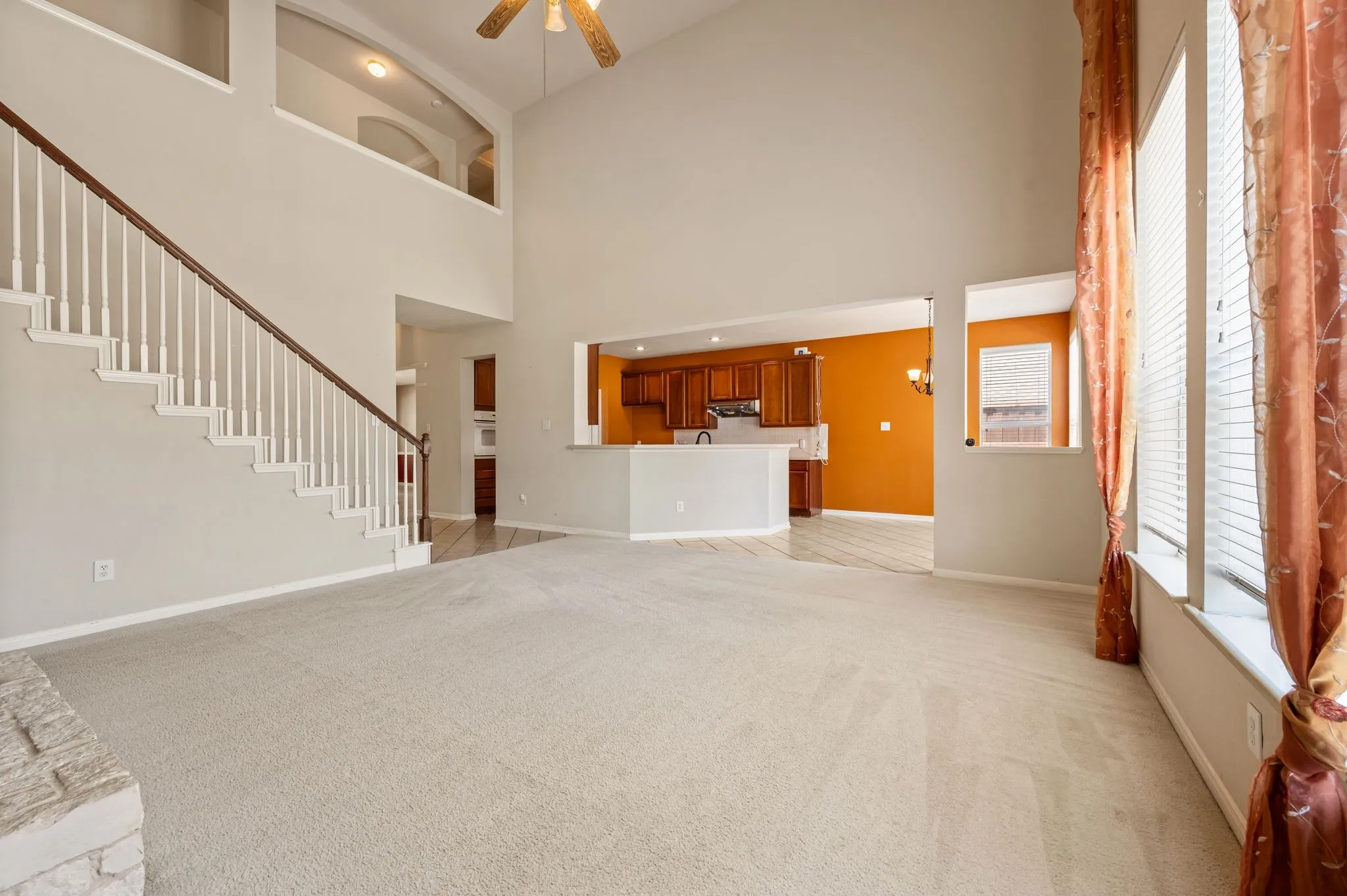 Two-story living area with high ceilings, an open staircase, and expansive windows