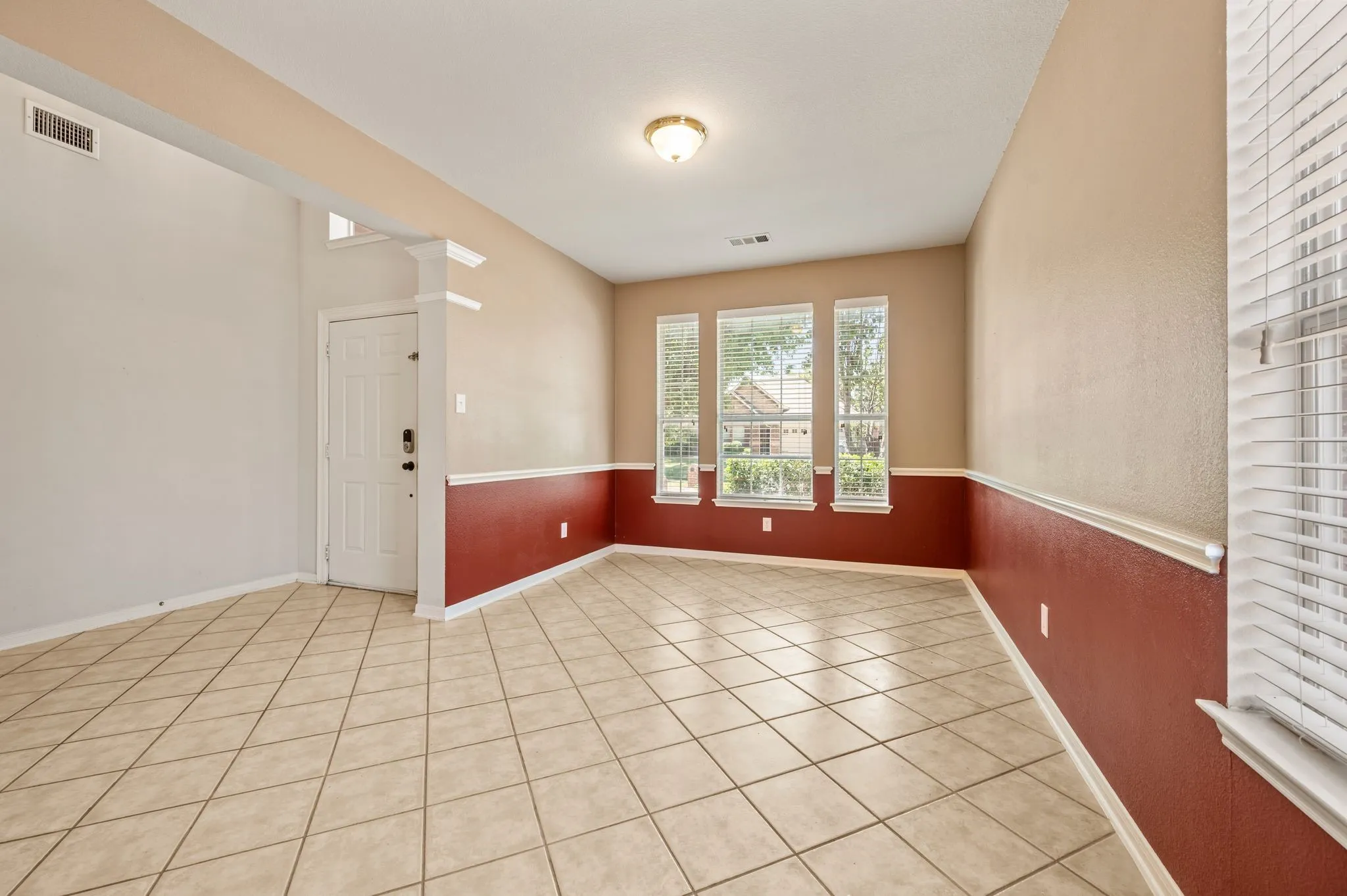 Tiled flooring, multiple windows with blinds, two-tone painted walls, and an overhead light fixture