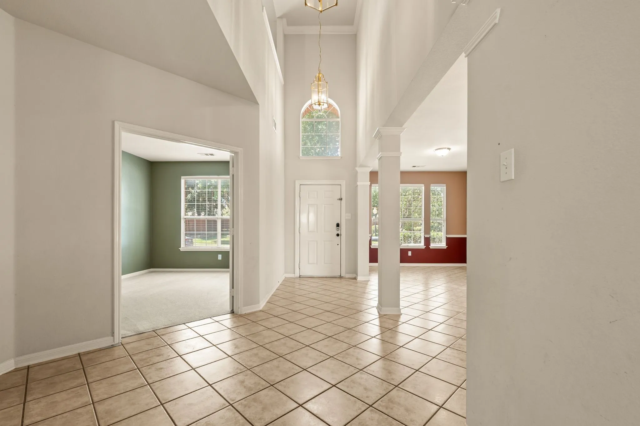 Two-story foyer featuring an arched transom window and ceramic tile flooring