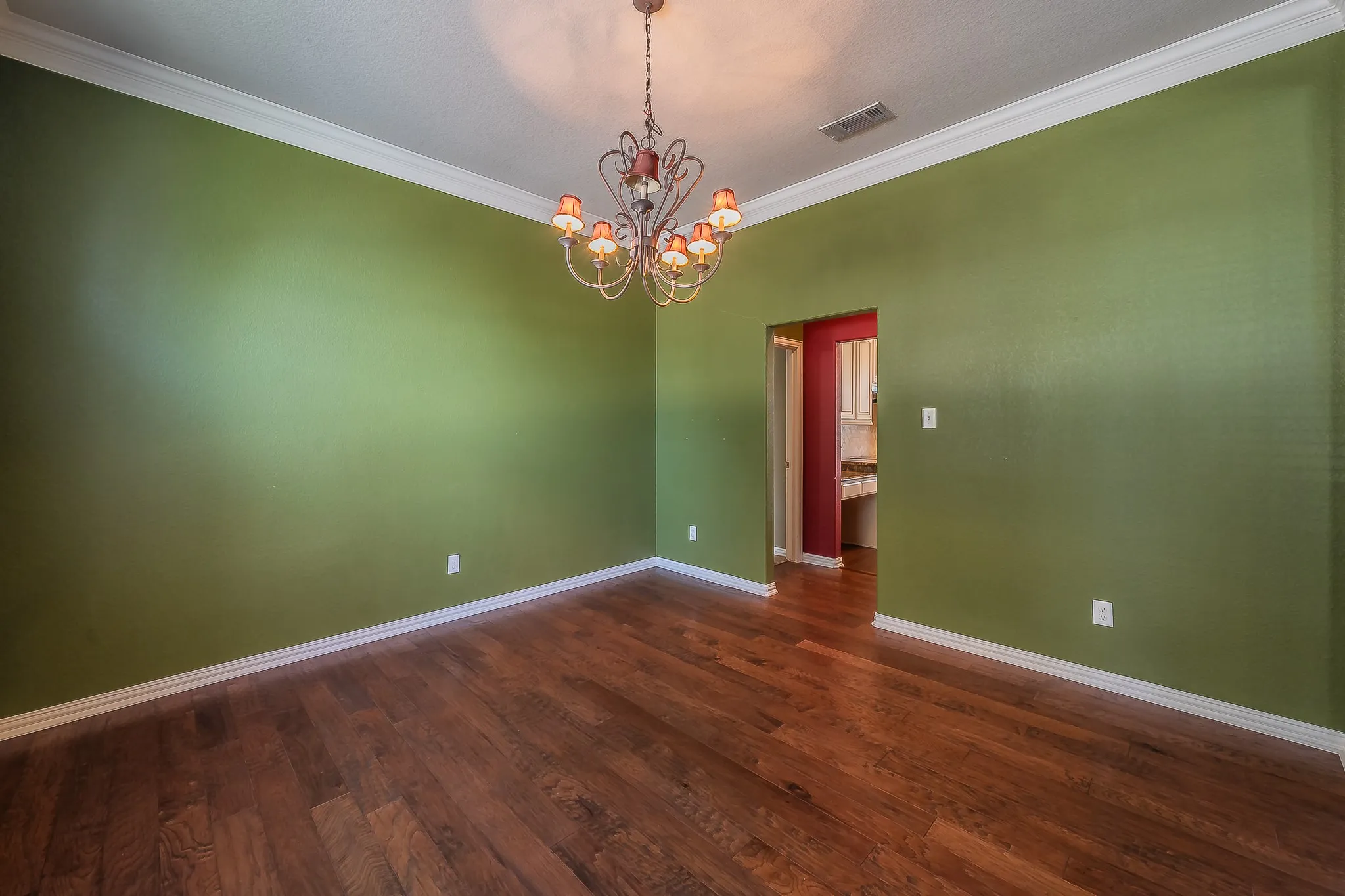 Hardwood flooring, crown molding, and a chandelier fixture