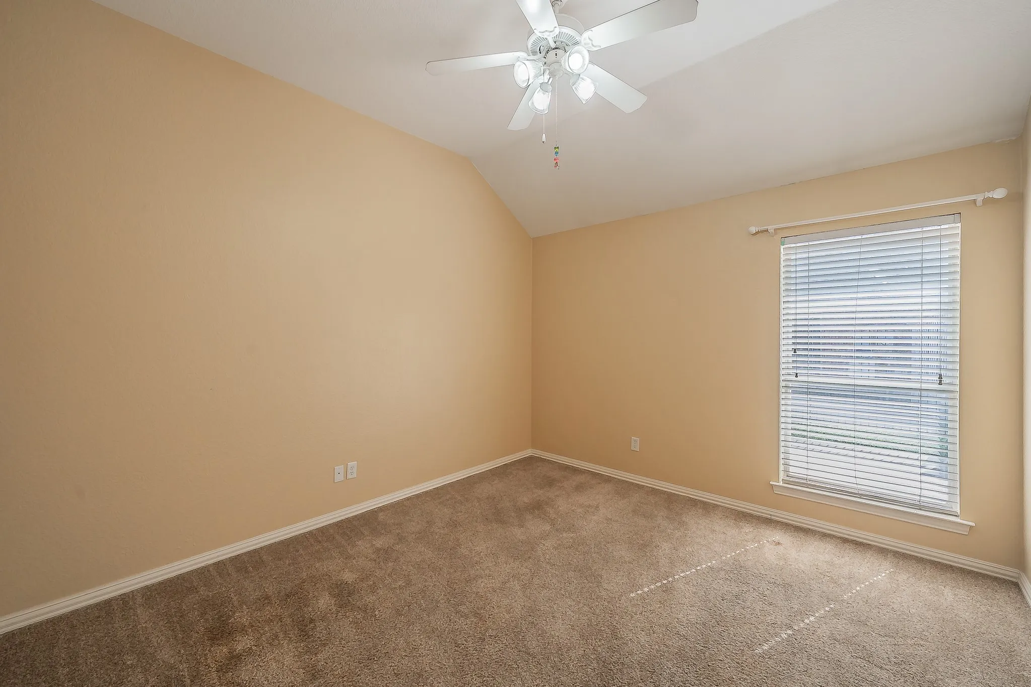 Carpeted room featuring a sloped ceiling and a window with blinds