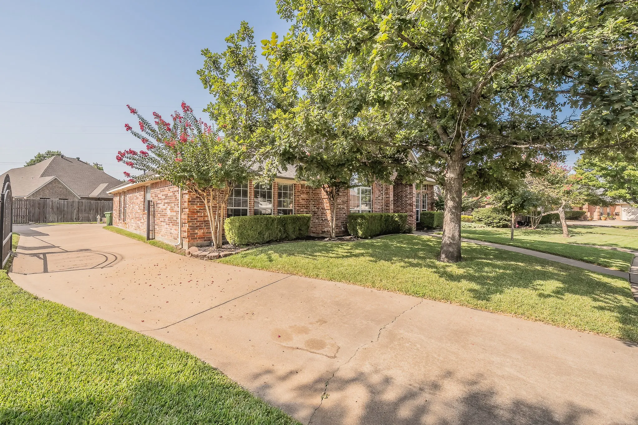 Brick exterior with a concrete driveway and mature trees