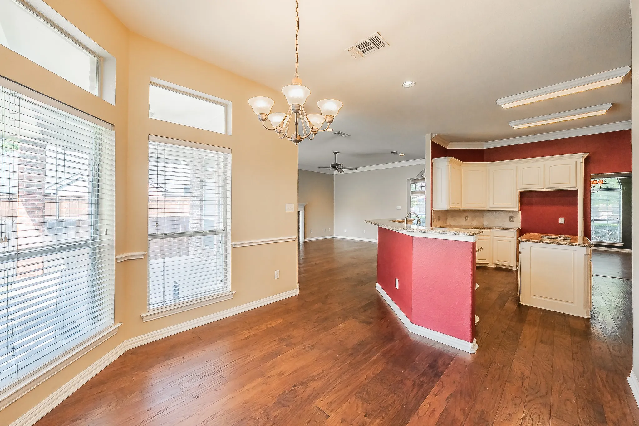 Spacious dining area featuring wood-finish flooring, a decorative chandelier, and abundant natural light from multiple windows