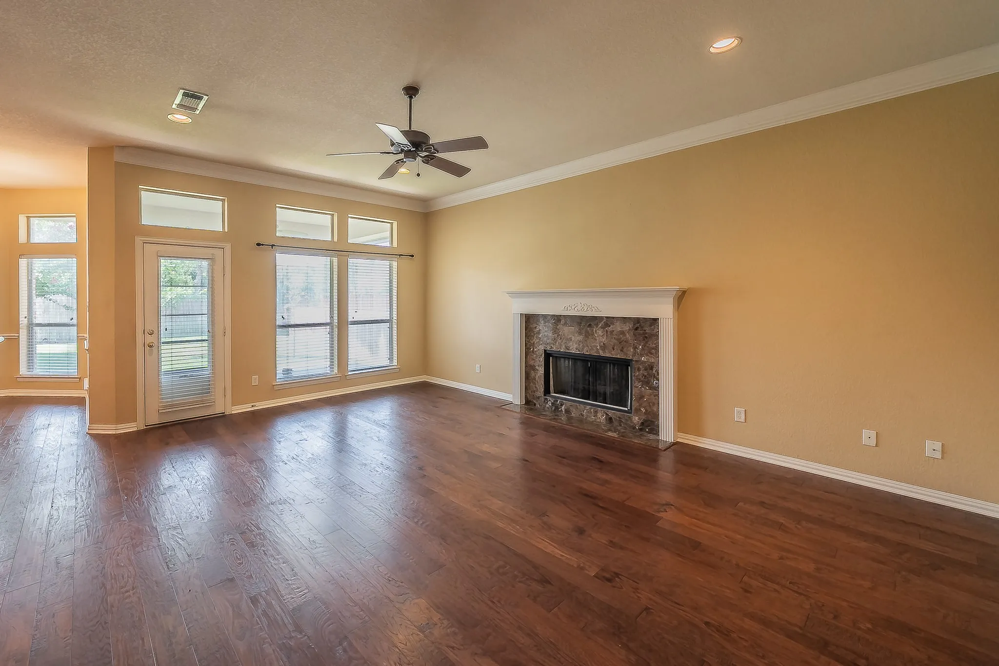 Hardwood-finish flooring throughout, featuring a fireplace with a stone surround and ornate mantel