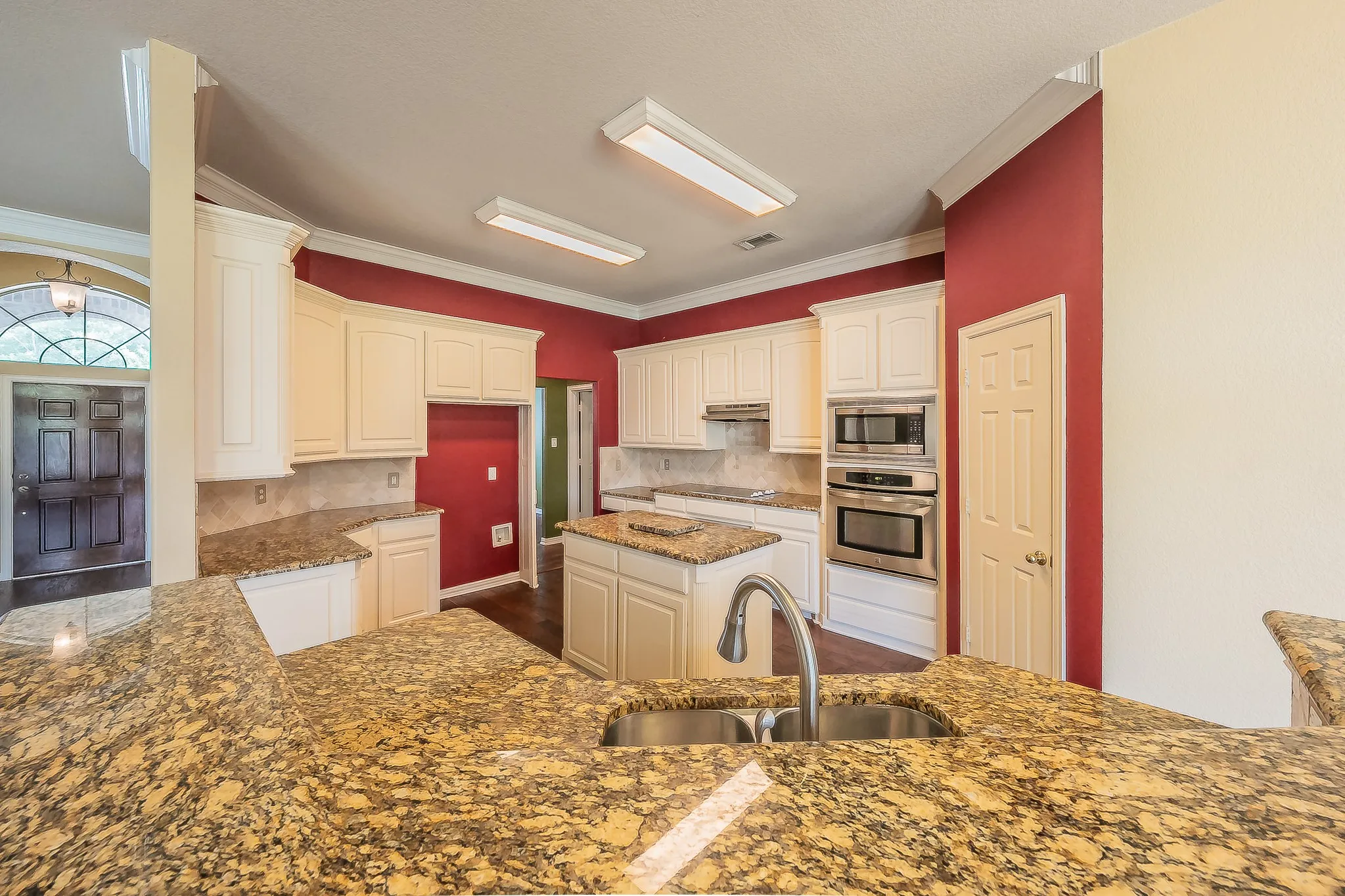 Kitchen featuring extensive countertops, stainless steel appliances, a center island, and white cabinetry