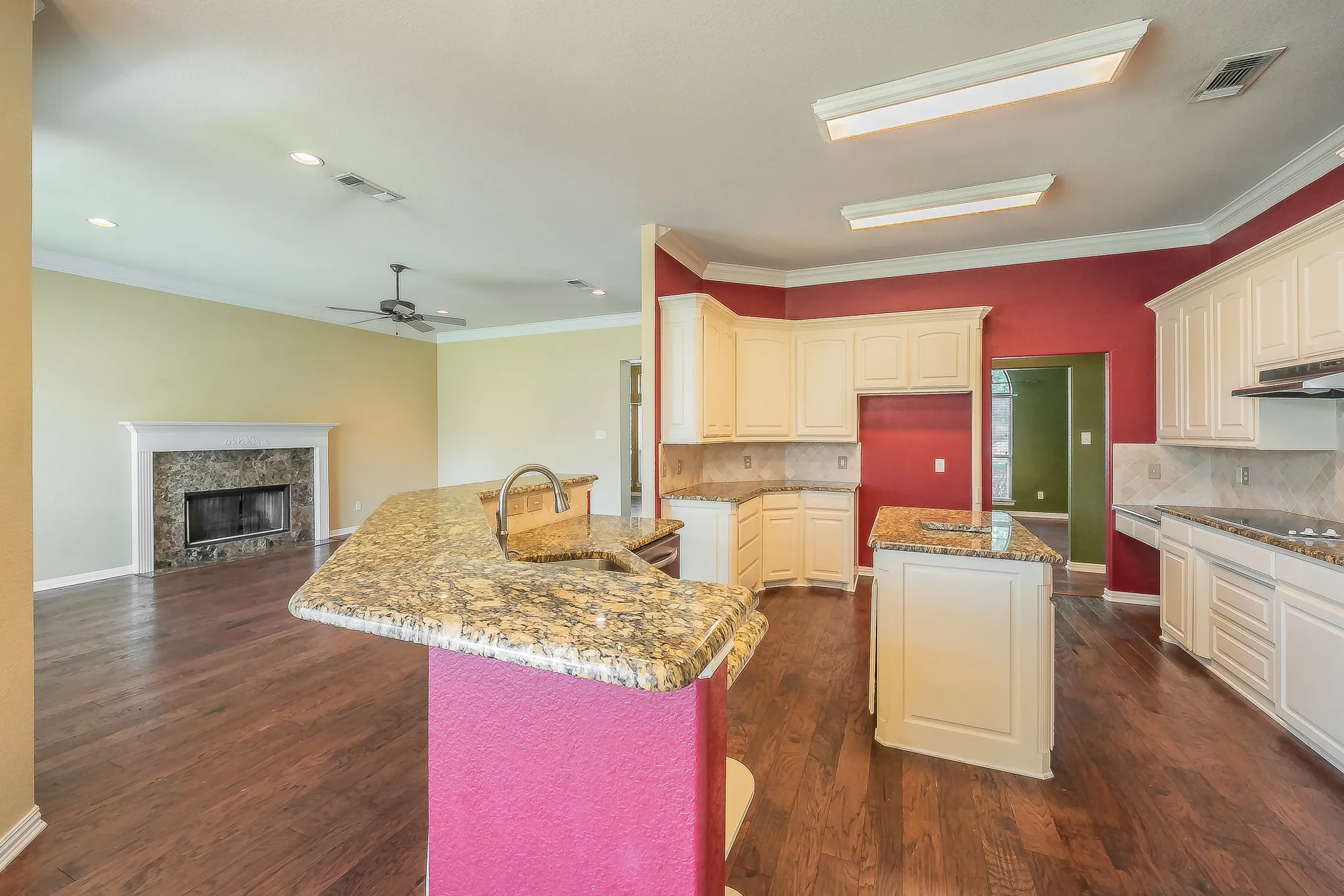 Kitchen featuring an island, granite countertops, tile backsplash, and white cabinetry