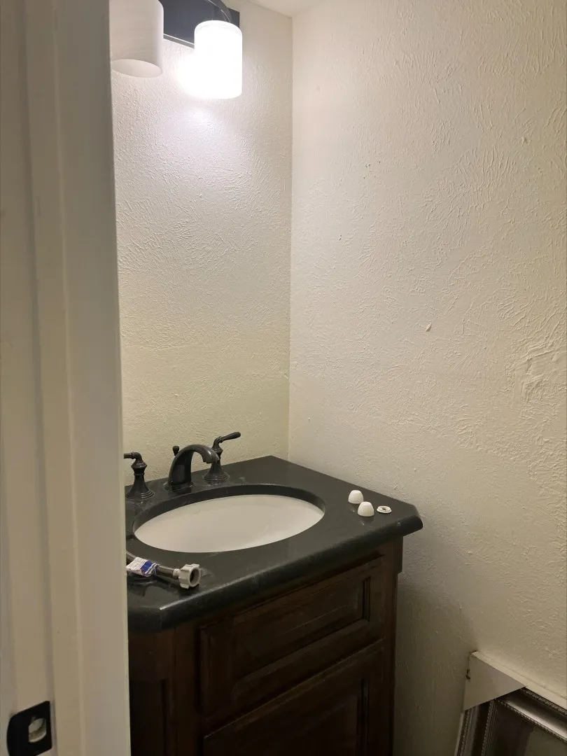 Vanity with dark wood cabinetry, dark countertop, and an integrated white sink