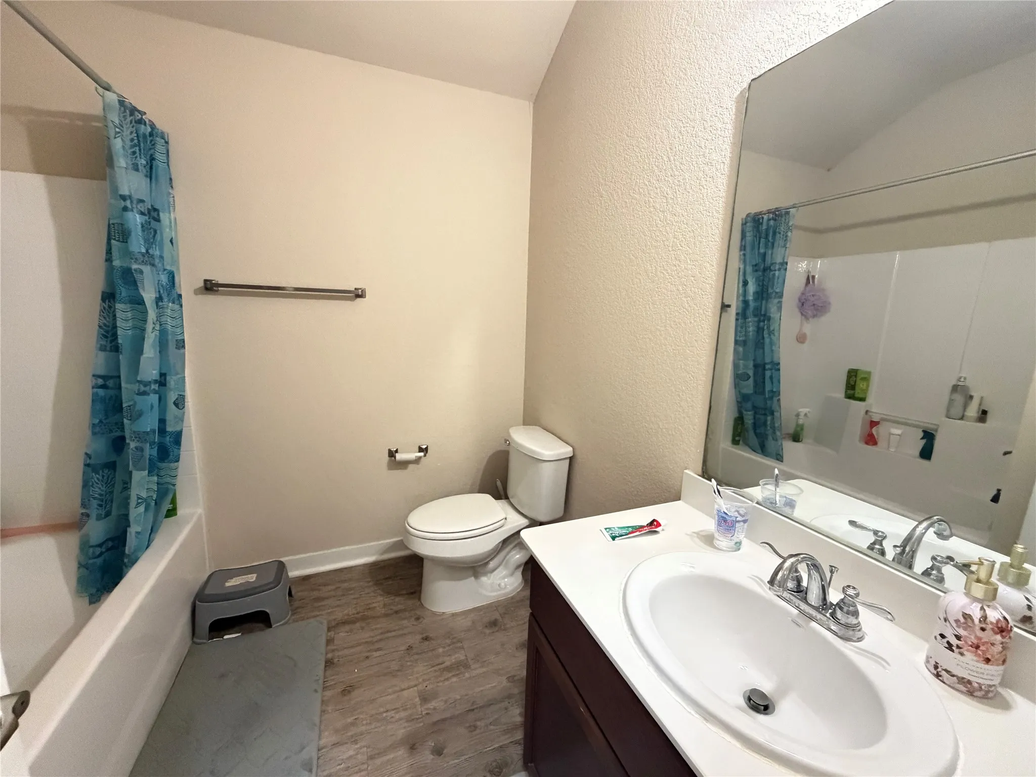 Single vanity with a white countertop and oval sink, set against wood-finish flooring