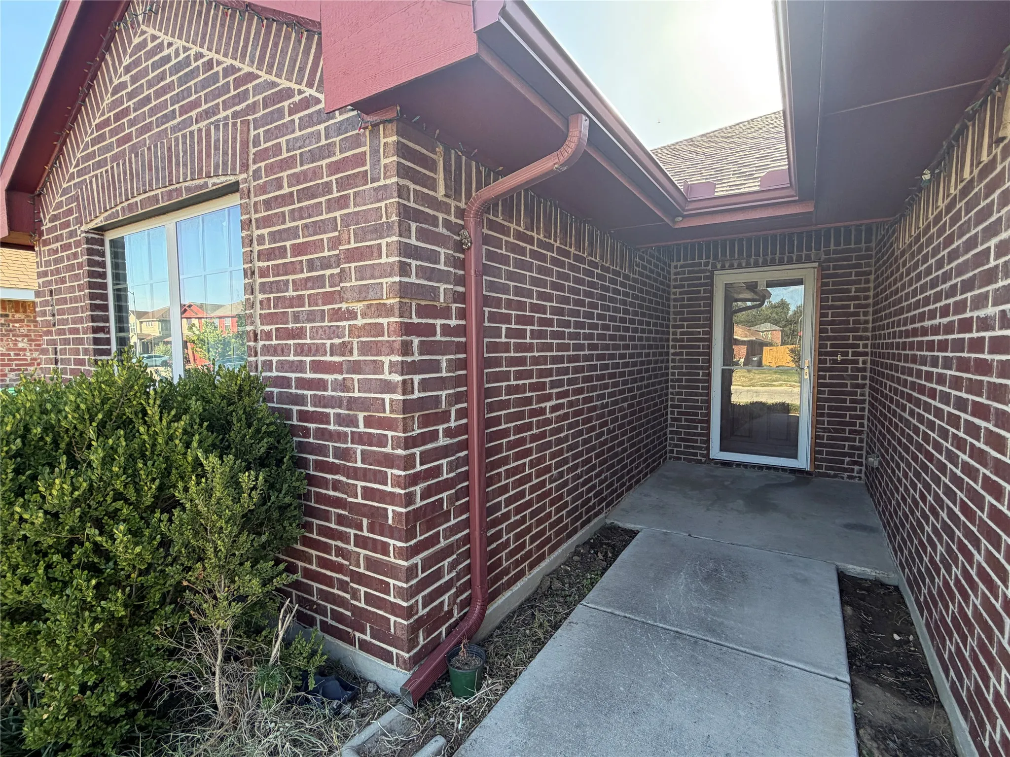 Brick exterior with a covered entry, white-framed door, and concrete walkway