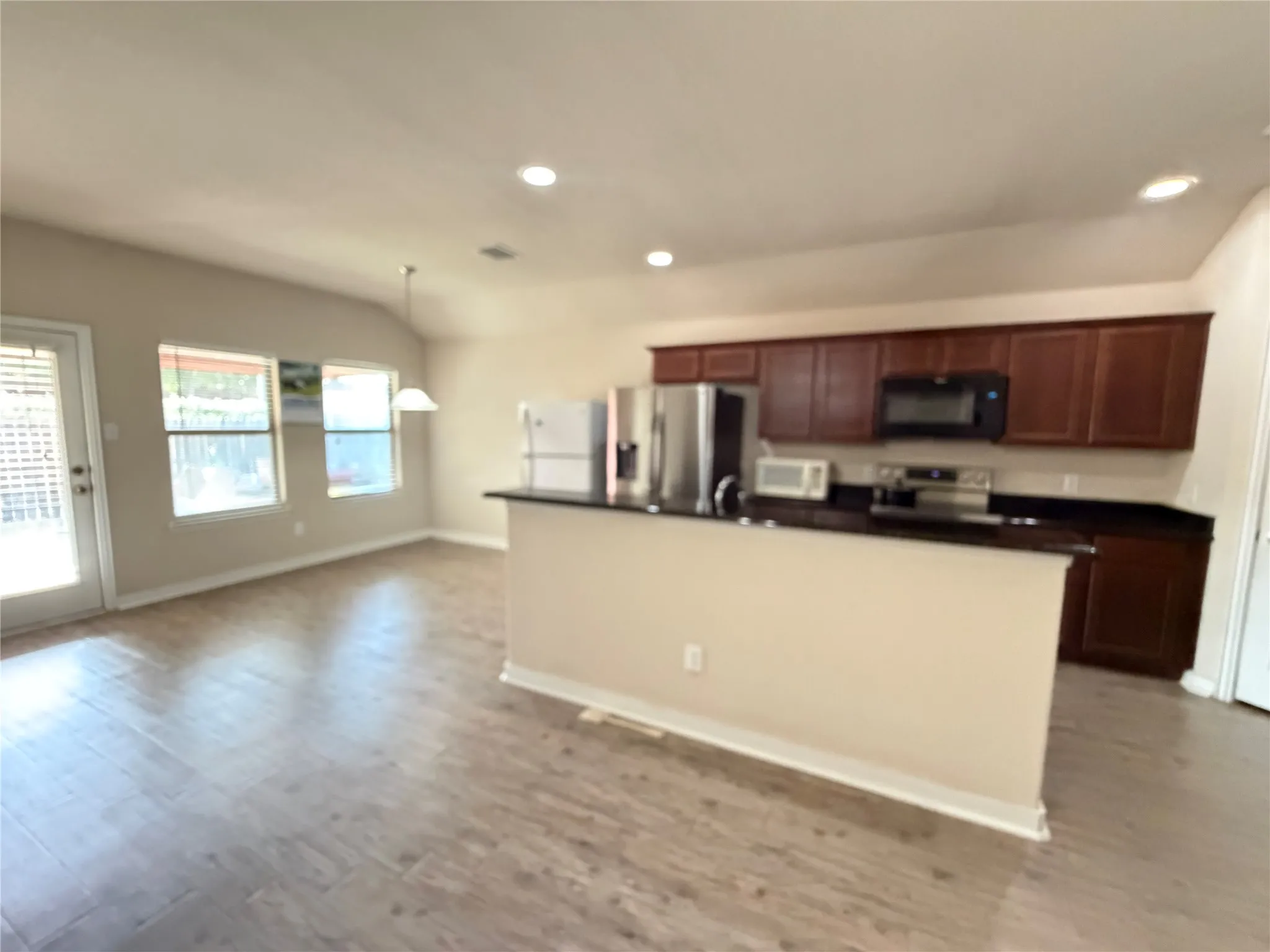 Kitchen featuring dark wood cabinetry, black countertops, and stainless steel appliances