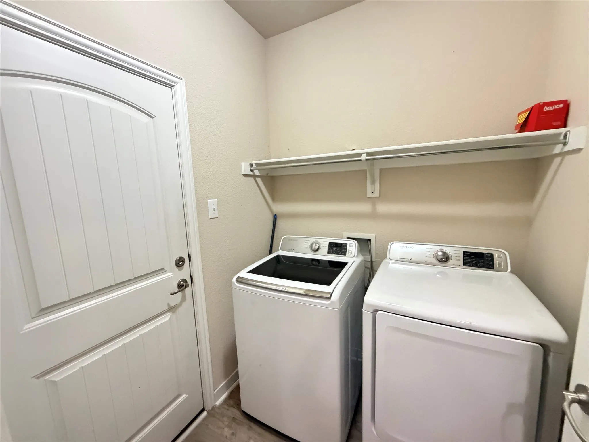 Utility area featuring a paneled door, built-in shelving, and wood-finish flooring