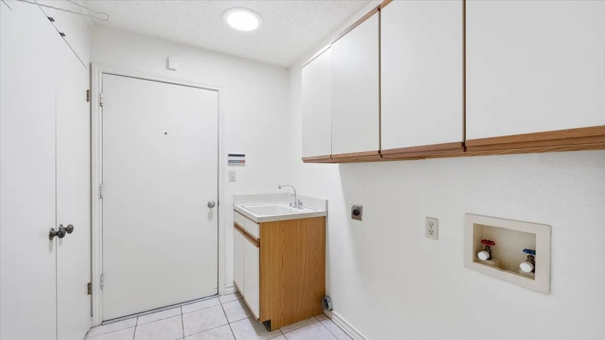 Laundry area with room for full-size washer and dryer, built-in cabinets and sink.