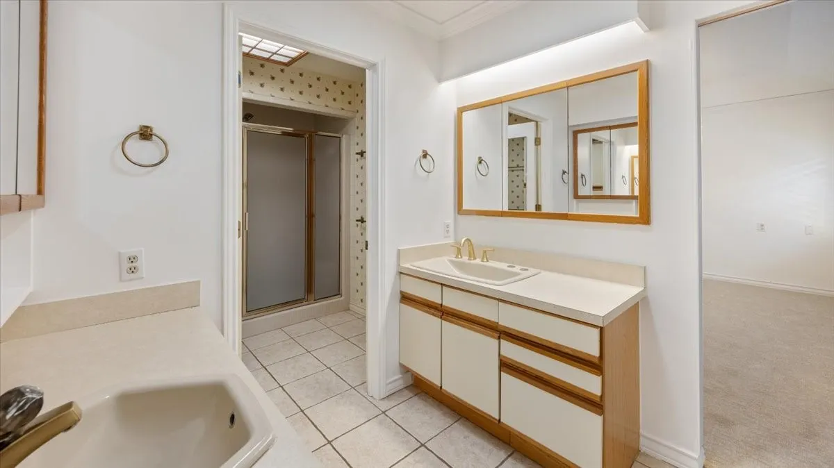 Dual vanity with integrated sinks and countertops, wood-finish cabinetry, mirrored medicine cabinet, and tile flooring