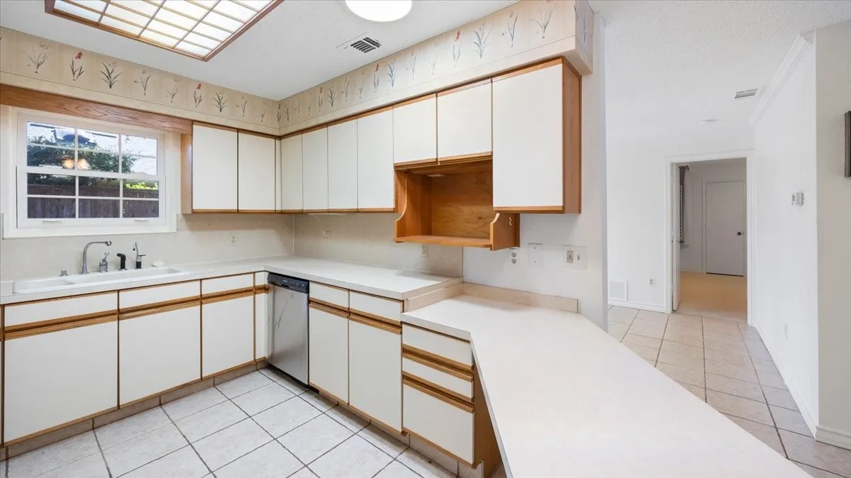 U-shaped kitchen layout with white cabinetry, light-toned countertops, and a built-in stainless steel dishwasher