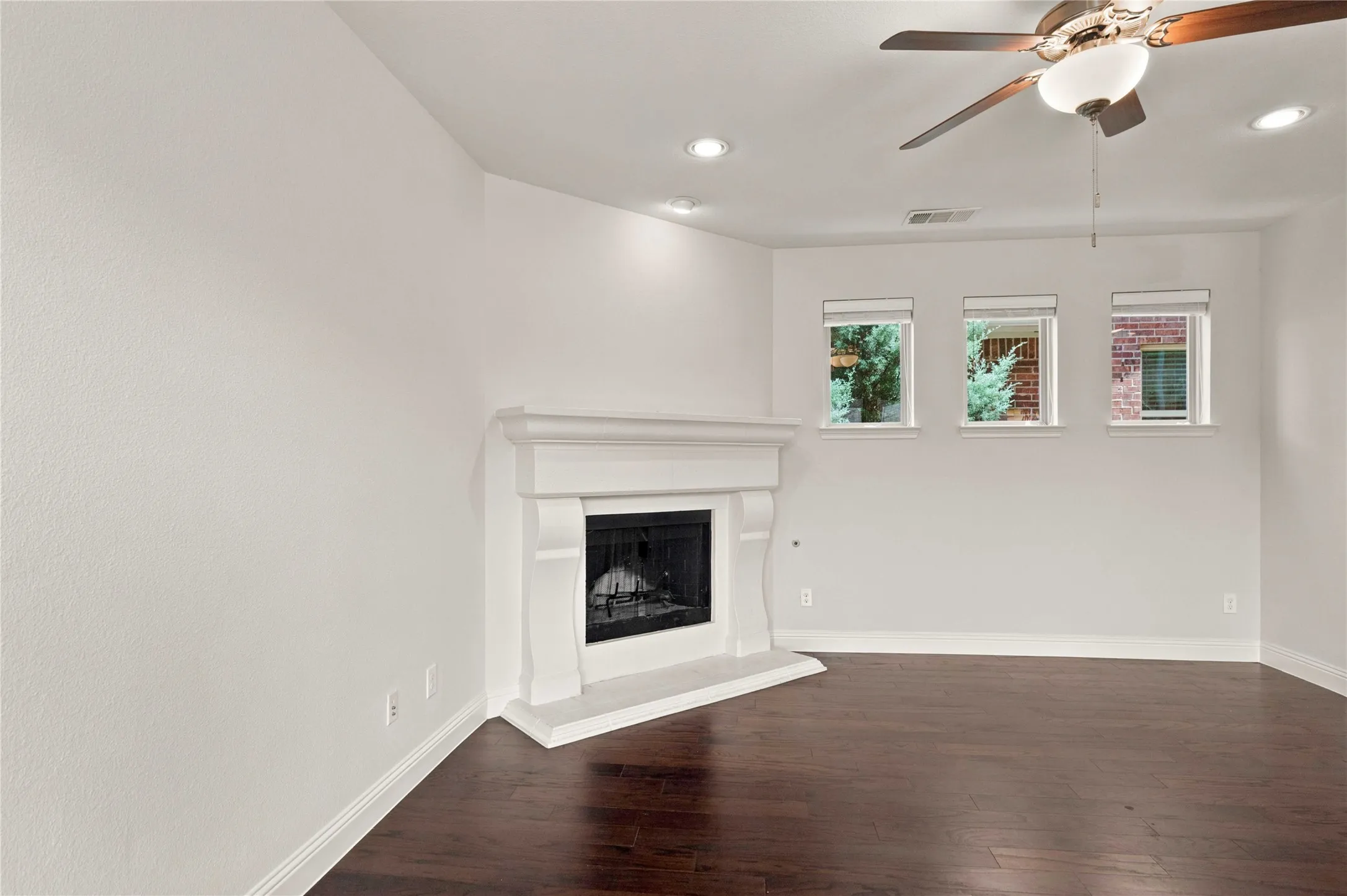 Hardwood-finish flooring, white walls, recessed lighting, ceiling fan, and a fireplace with a mantel
