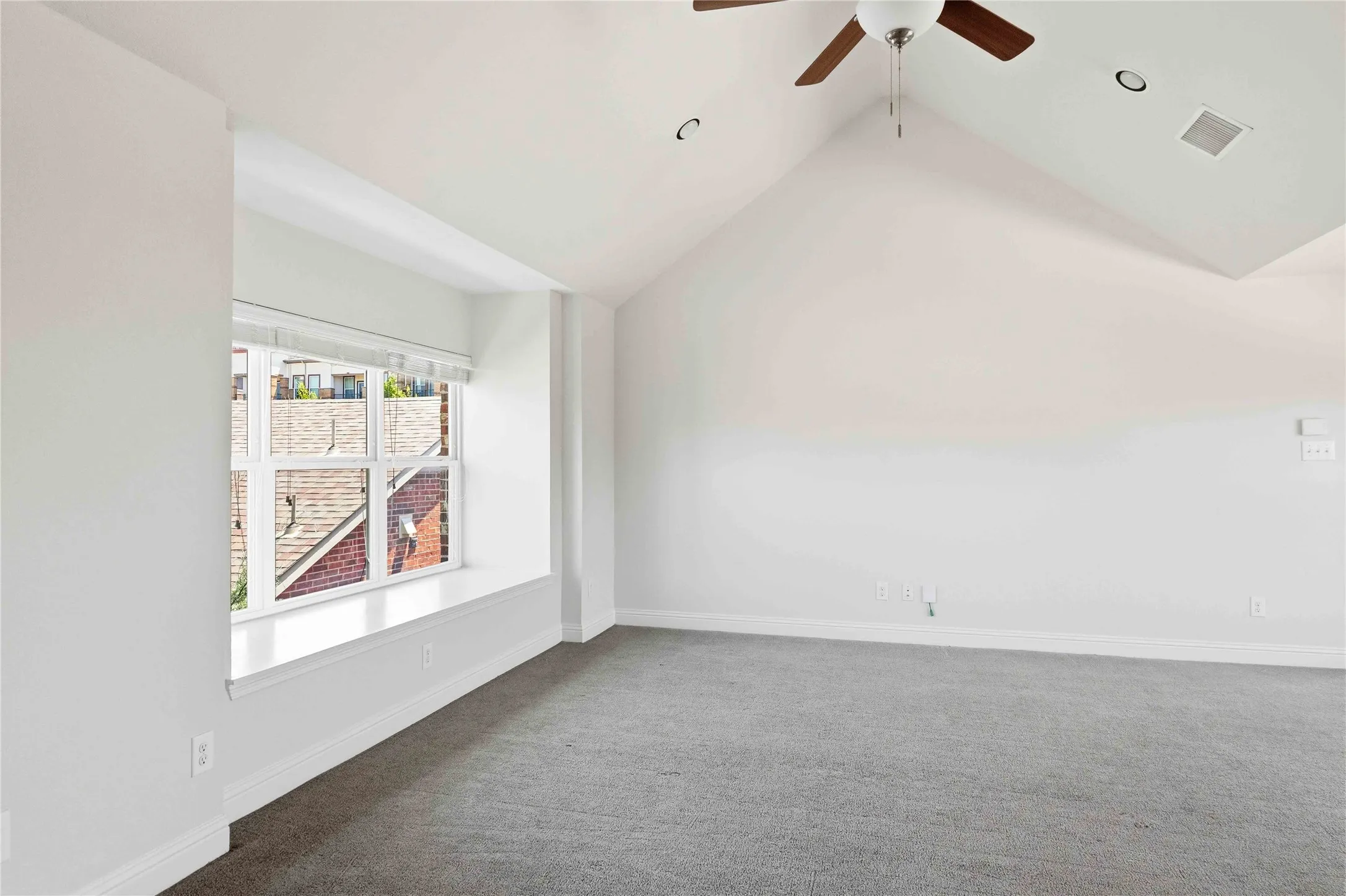Bright, light-filled room with soaring vaulted ceilings and ceiling fan, expansive windows with natural light, neutral wall finishes, and plush carpeting throughout