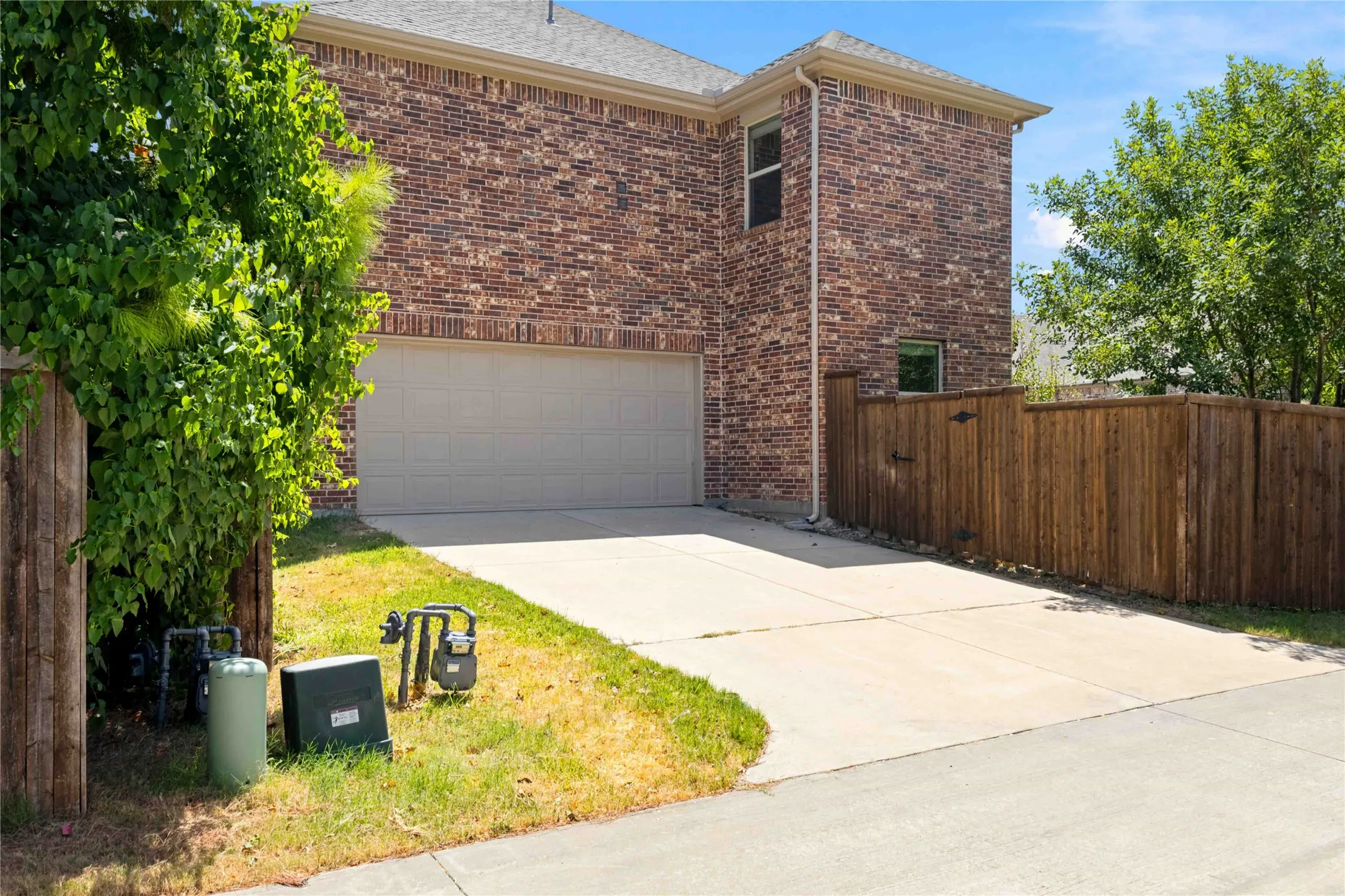 Brick exterior with light-colored garage door and concrete driveway