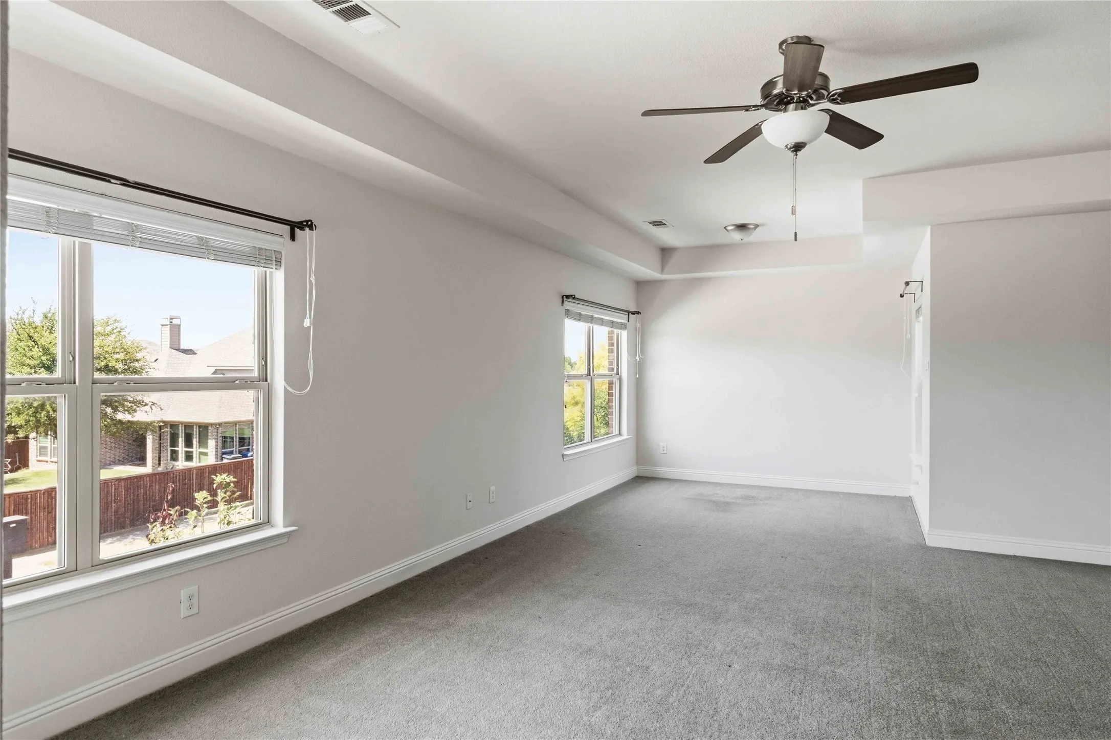 Bright, light-filled room with expansive windows offering natural illumination, neutral wall finishes, and gray carpet flooring