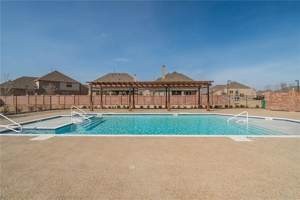 Outdoor swimming pool with integrated steps, a surrounding paved deck, and a wooden pergola structure