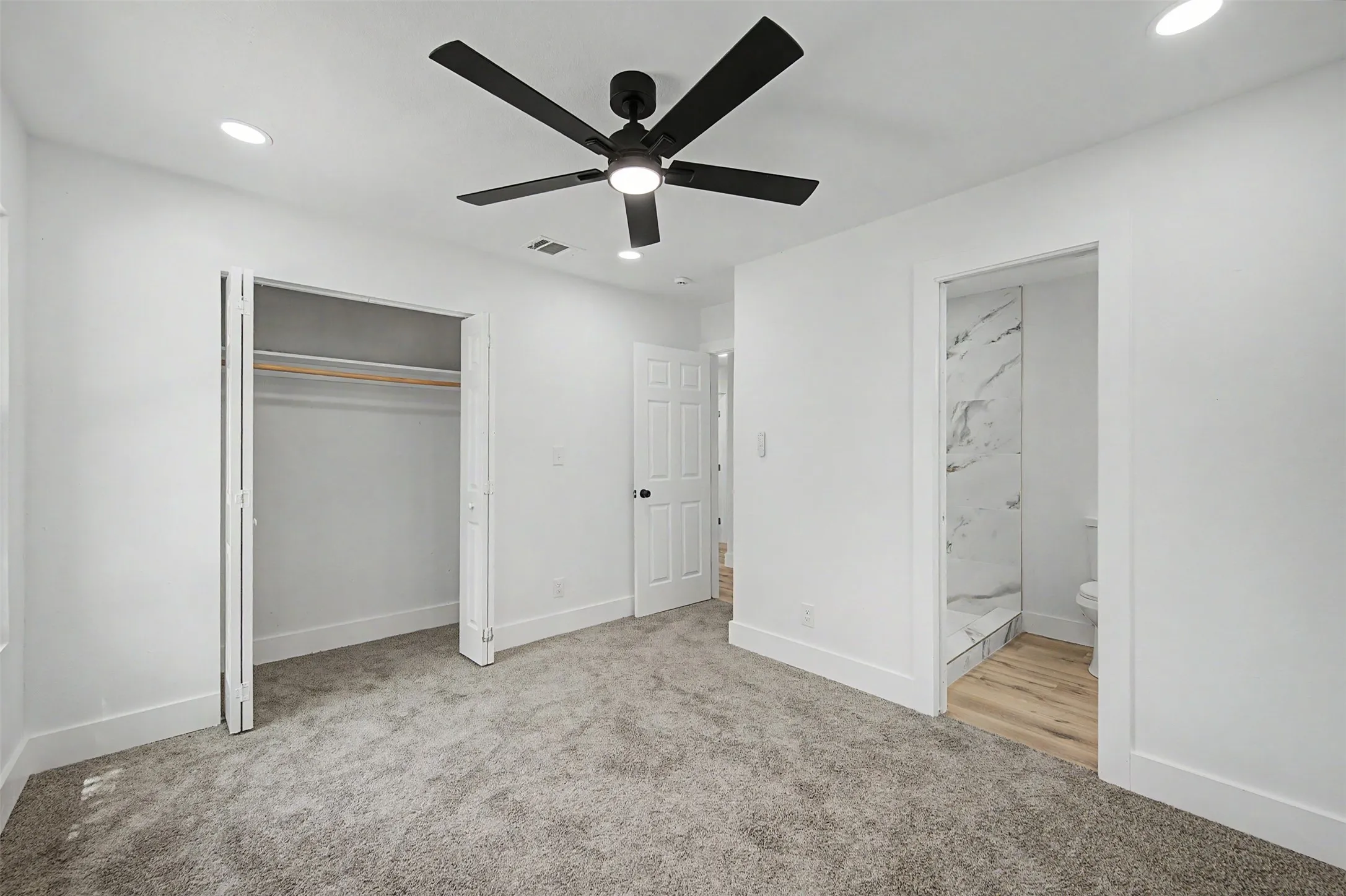 Recessed lighting, ceiling fan, bi-fold closet, wood-finish flooring, and a walk-in shower with a tile surround