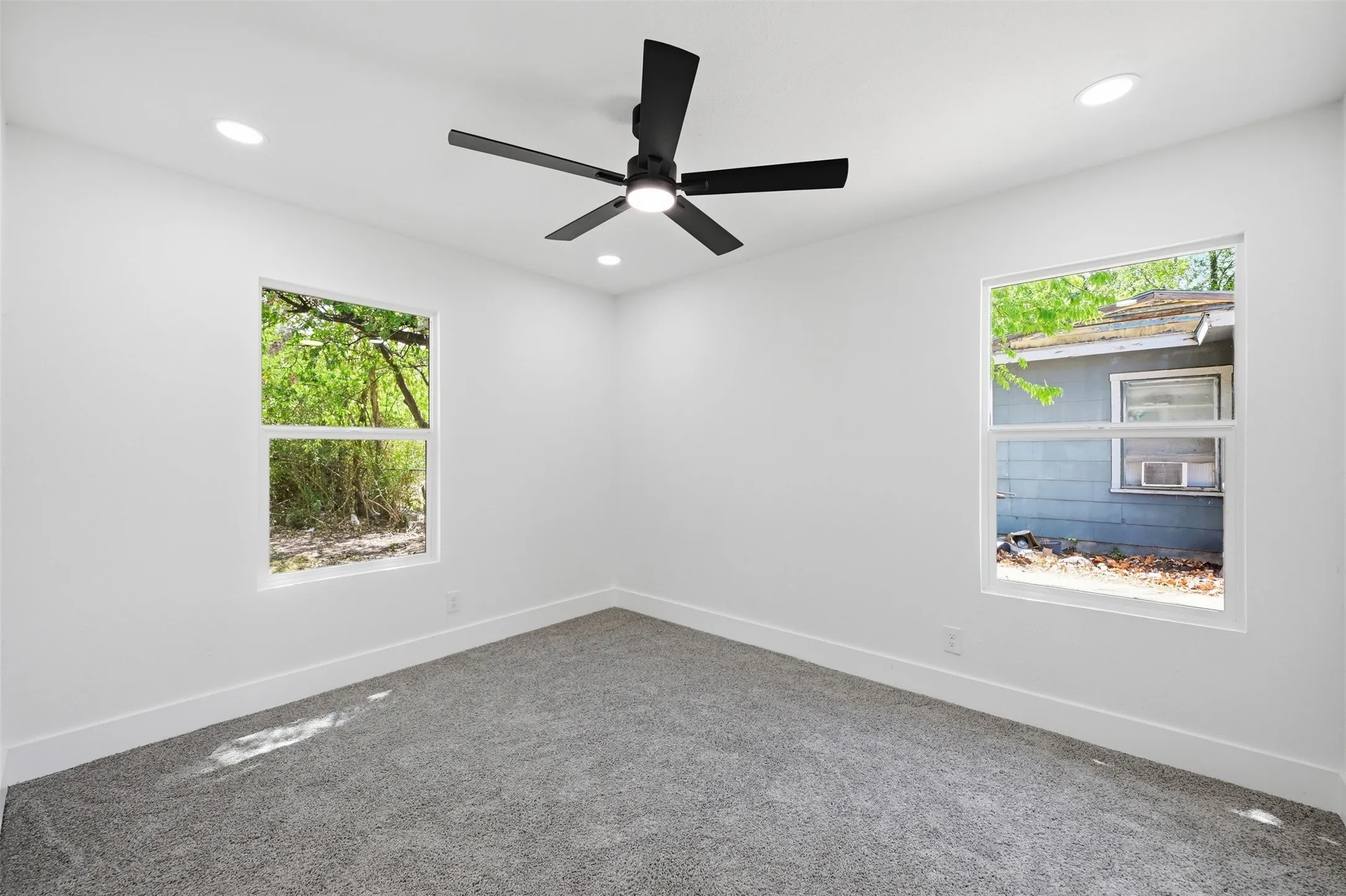 White walls, recessed lighting, matte black ceiling fan, and carpeted flooring