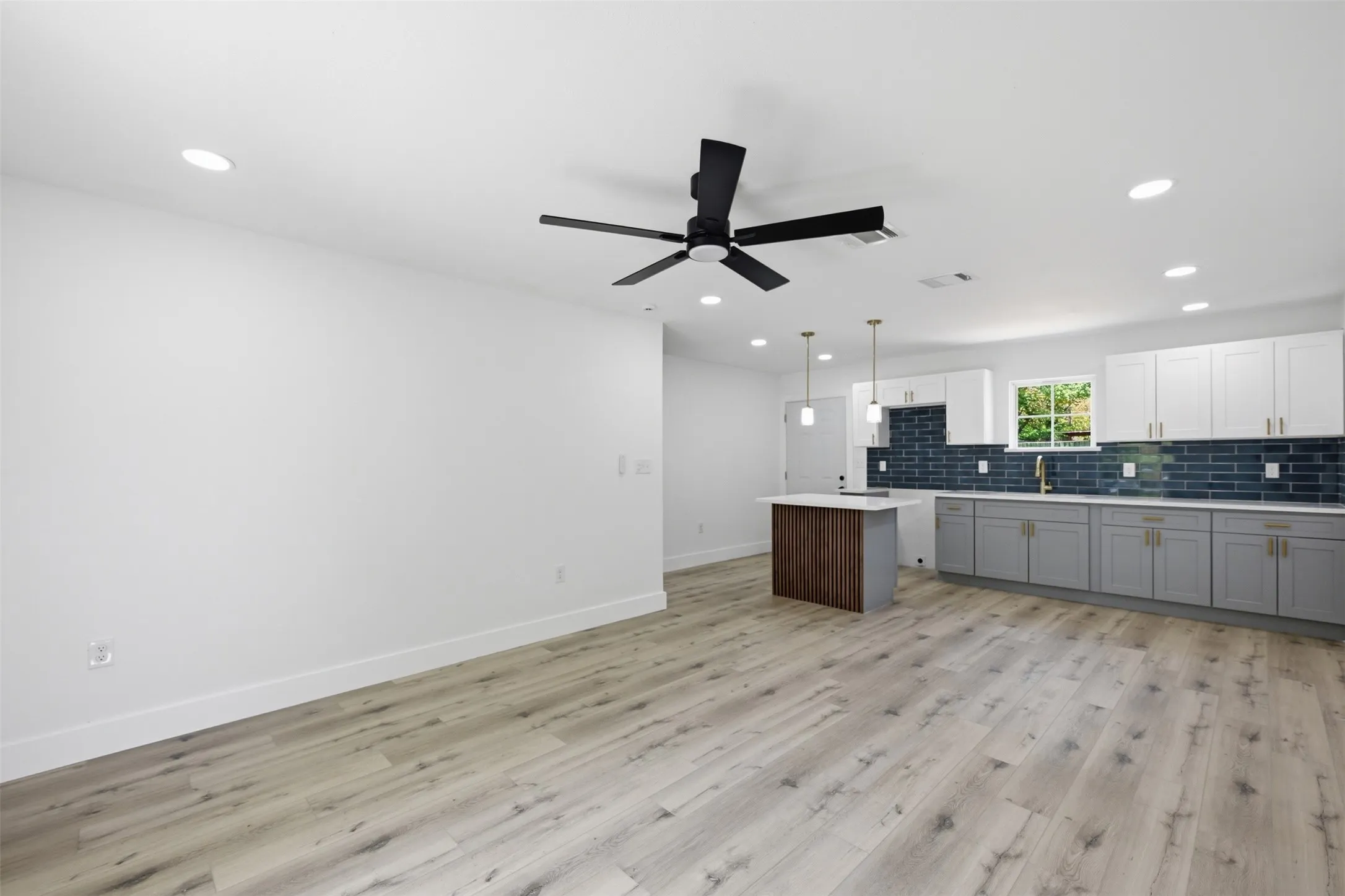 Open-concept living area with wood-finish flooring, recessed lighting, and a ceiling fan