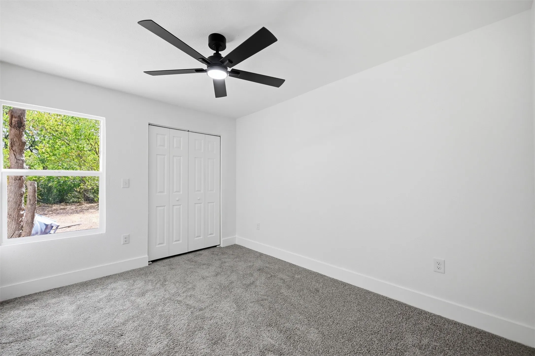 White walls, gray carpeting, and a white window frame