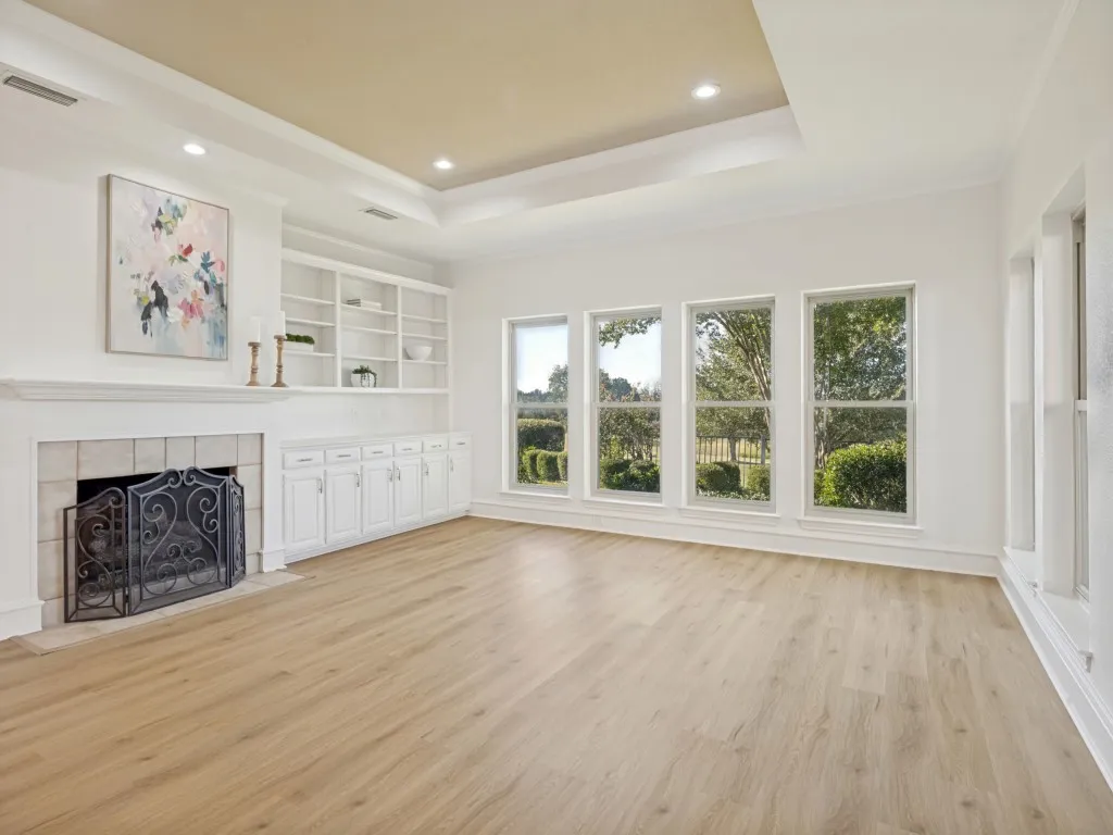 Very large great room with built-in cabinetry, tray ceiling, fireplace, recessed lighting and gorgeous new luxury vinyl plank floors.