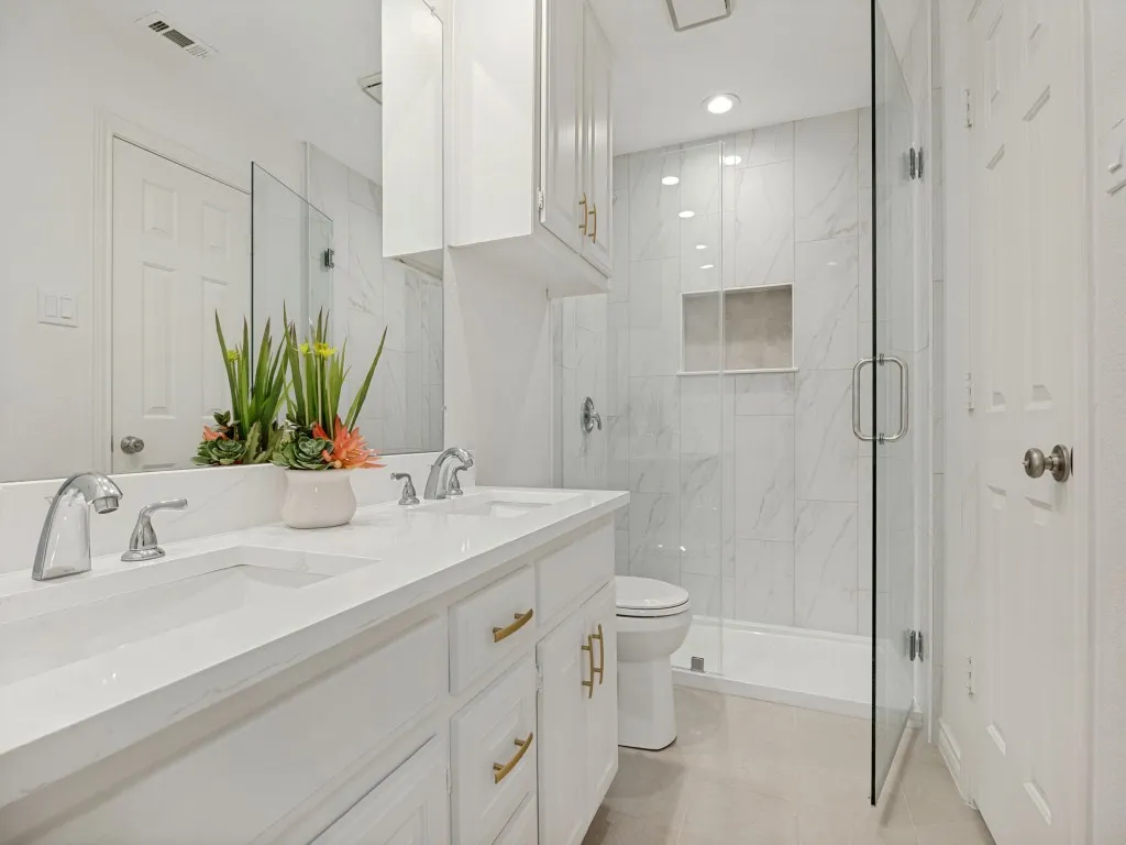 Updated Jack-and-Jill bathroom with seamless glass shower, new fixtures.