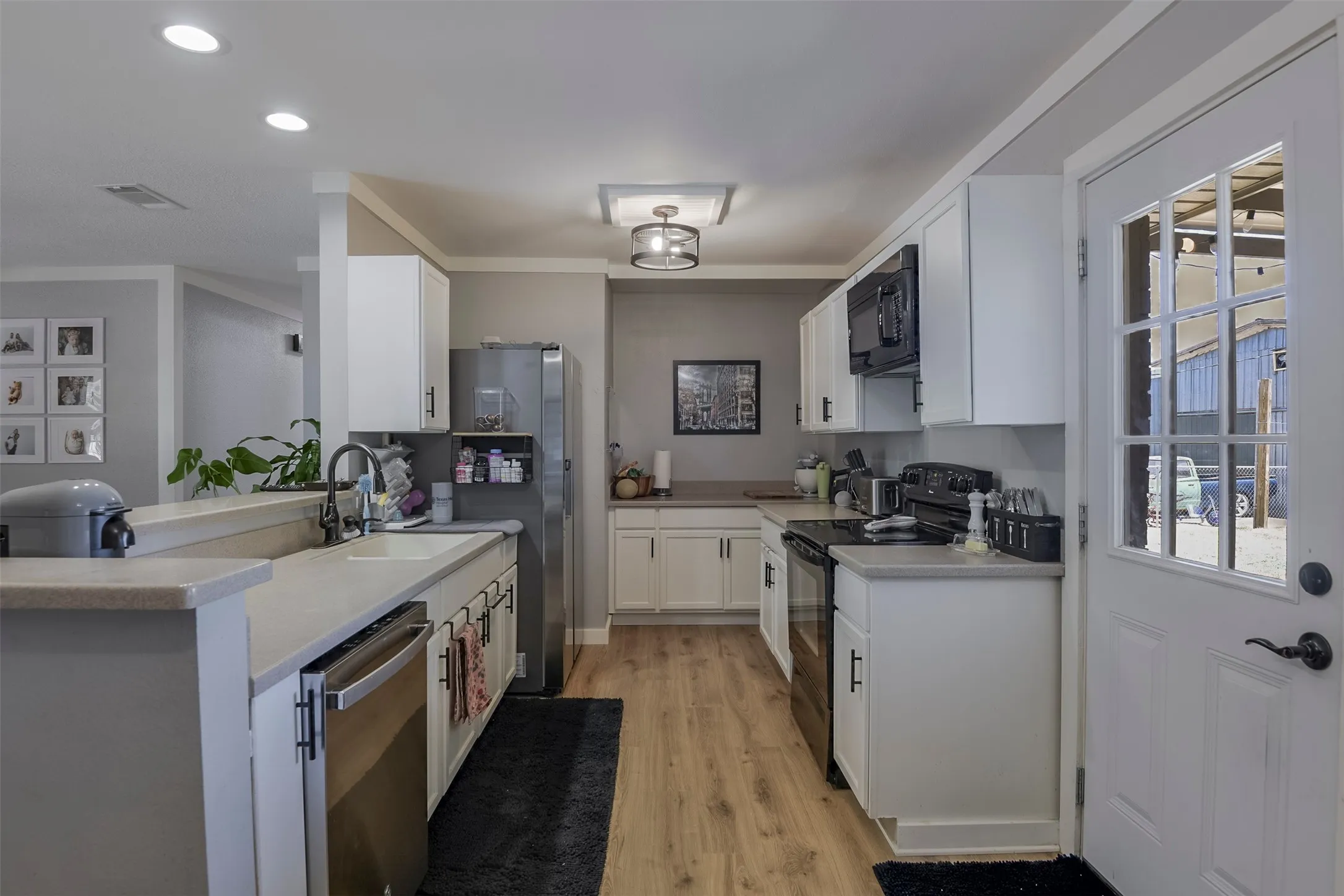 Kitchen featuring white cabinetry, light countertops, wood-finish flooring, and stainless steel appliances